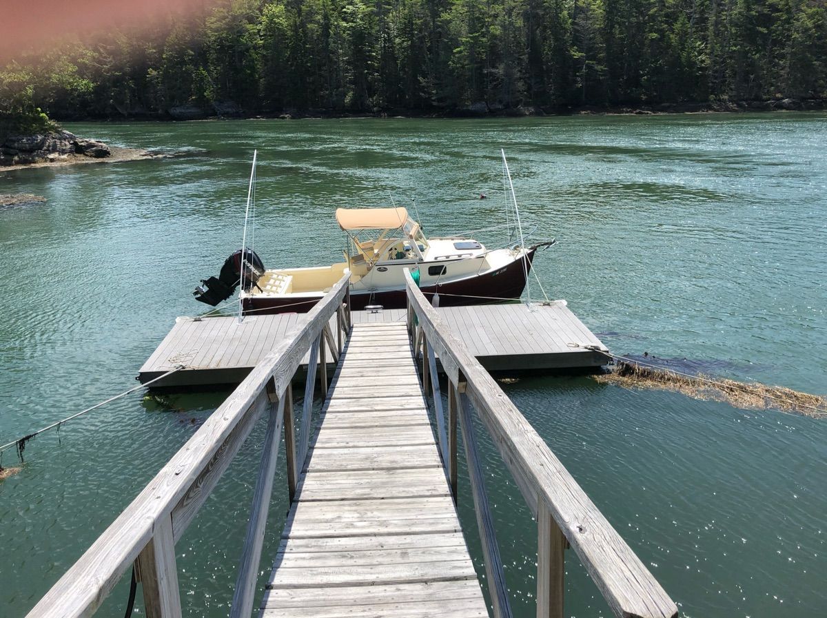 A 2018 Seaway Seafarer 21 boat docked at a wooden pier in a calm, wooded waterway.