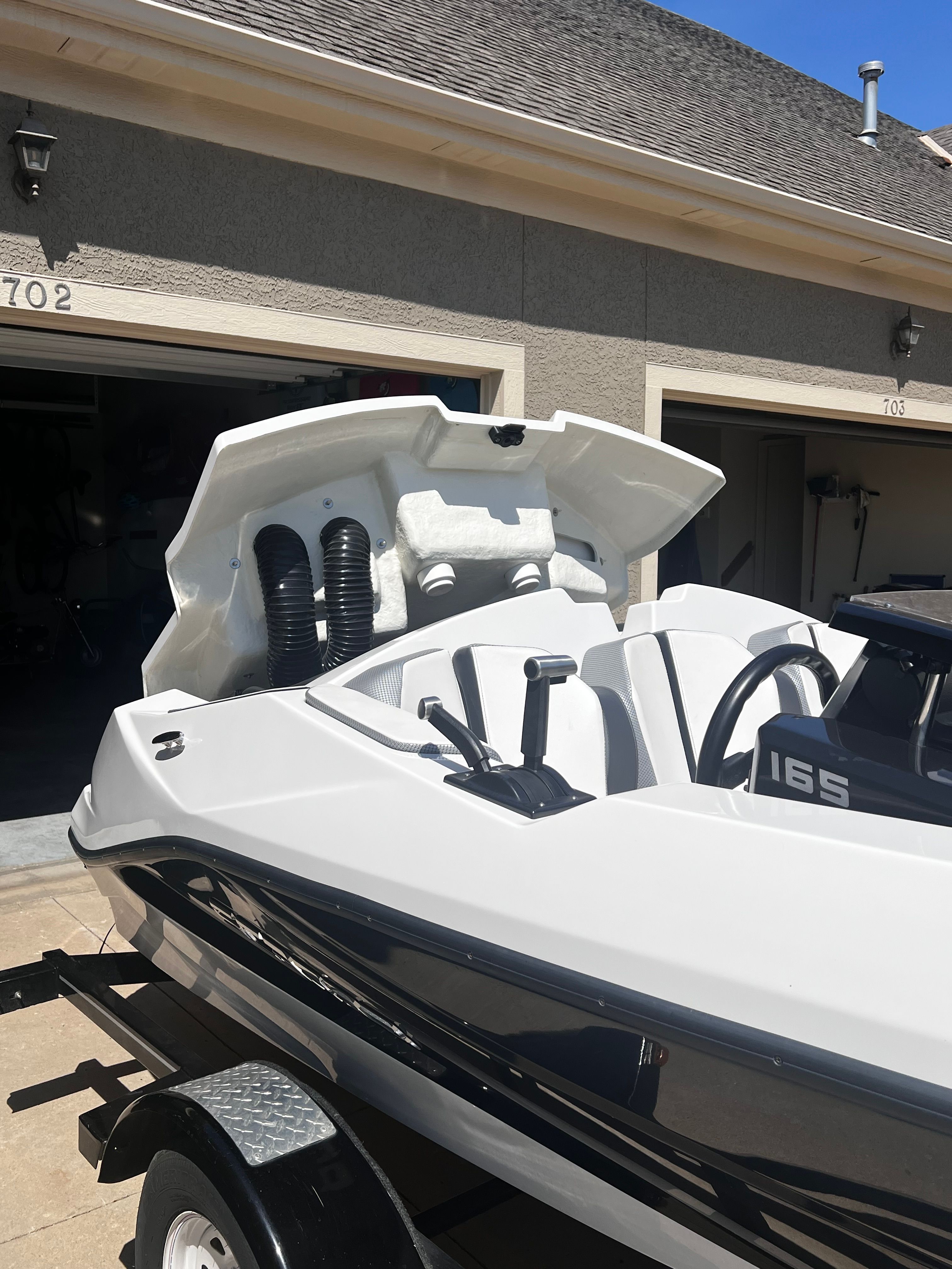 A white Scarab 165 G boat is on a trailer in a driveway.