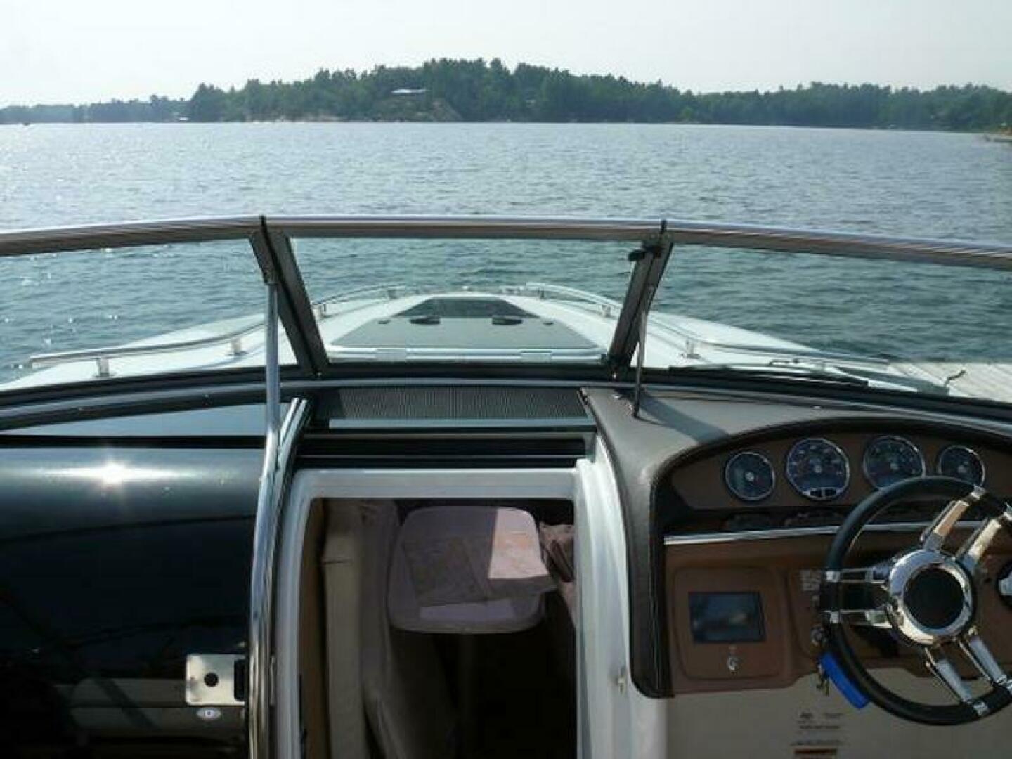2012 Cobalt 273 boat interior with steering wheel, dashboard, and open cabin on a lake.