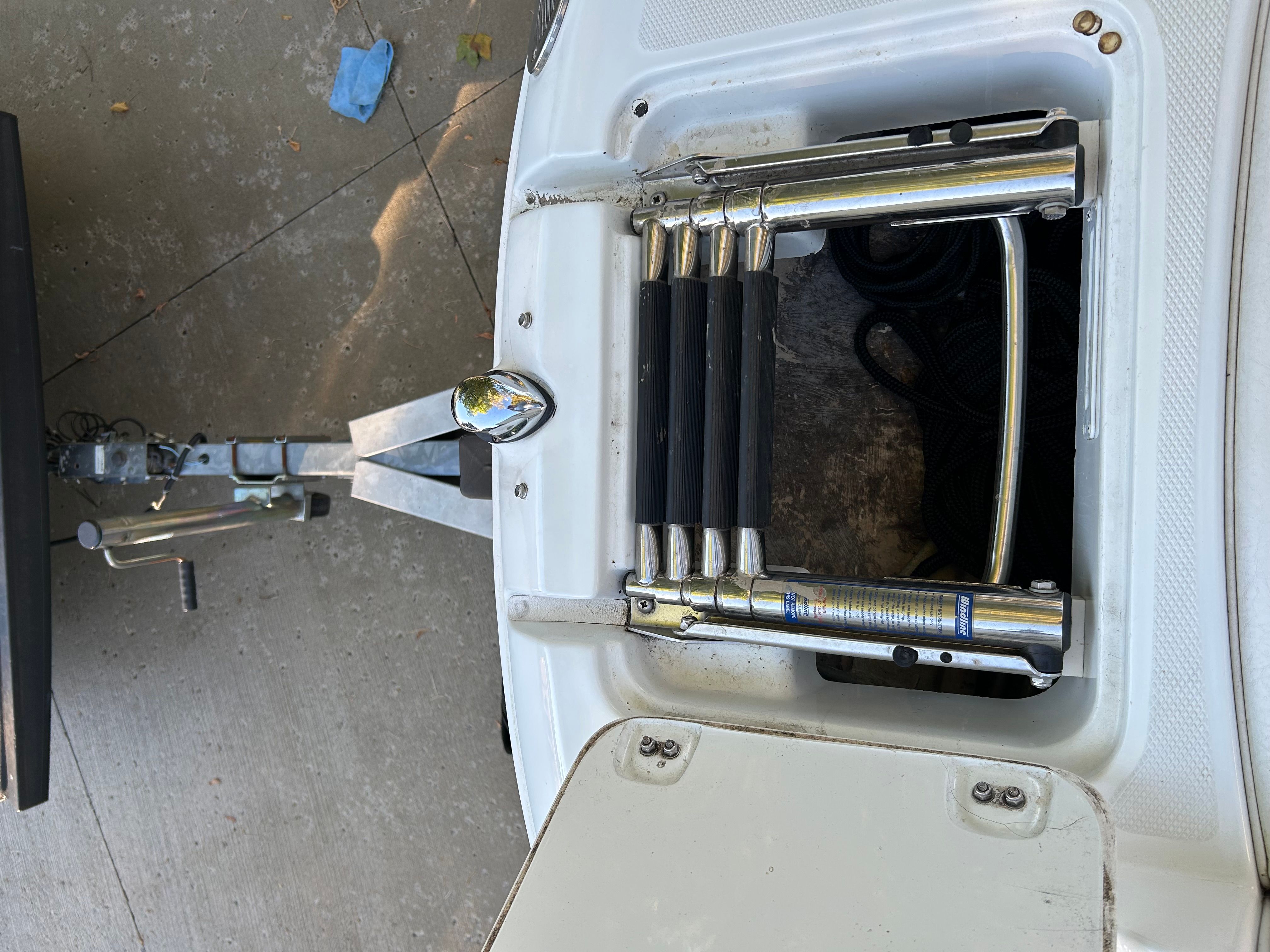 A folded swim ladder is visible in a storage compartment at the stern of a boat.