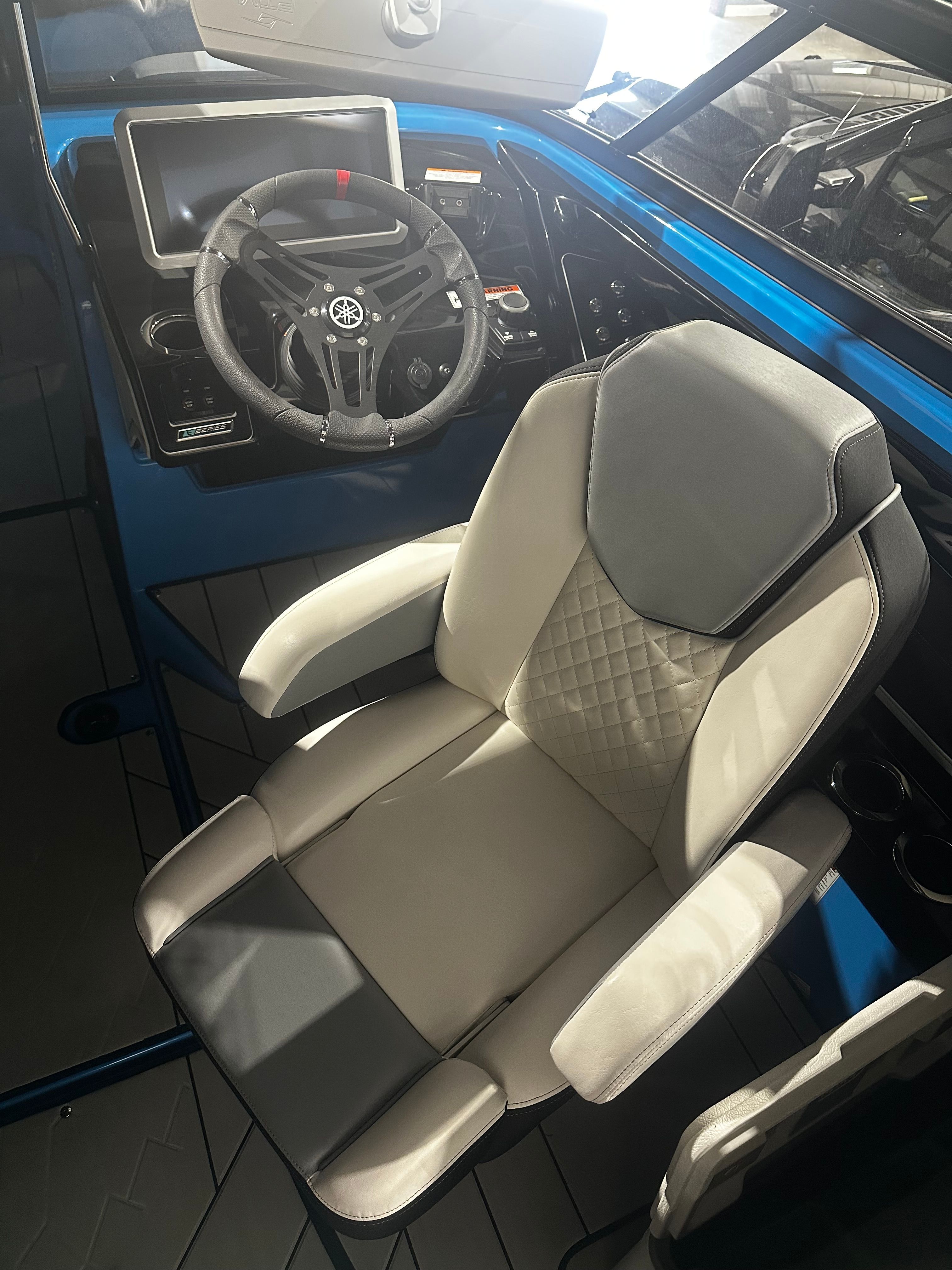 2023 Yamaha Boats 255XD cockpit with steering wheel and luxurious captain's chair.