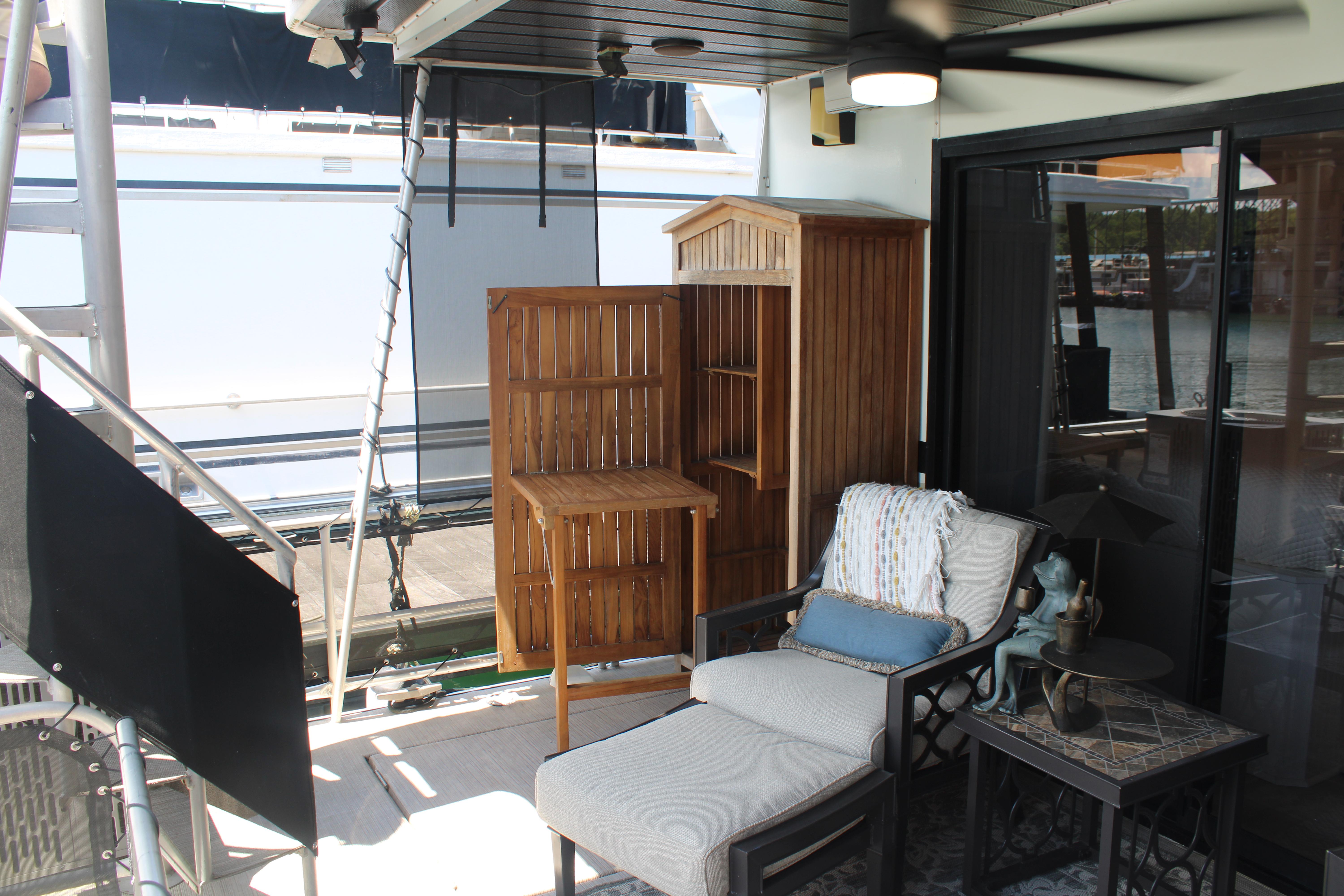 Cozy outdoor seating area on 1992 Sumerset 66 houseboat with wooden furniture and lake view.