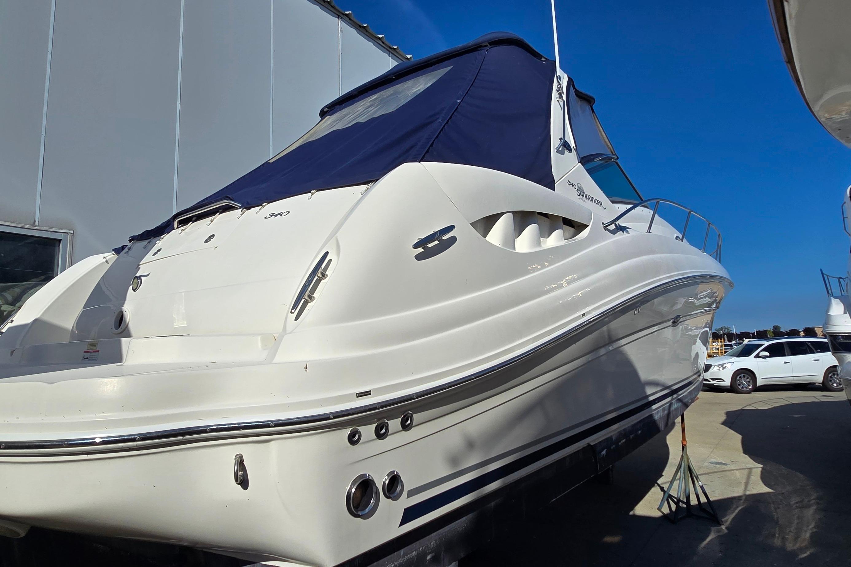 2007 Sea Ray 340 Sundancer boat with blue cover, docked outdoors.