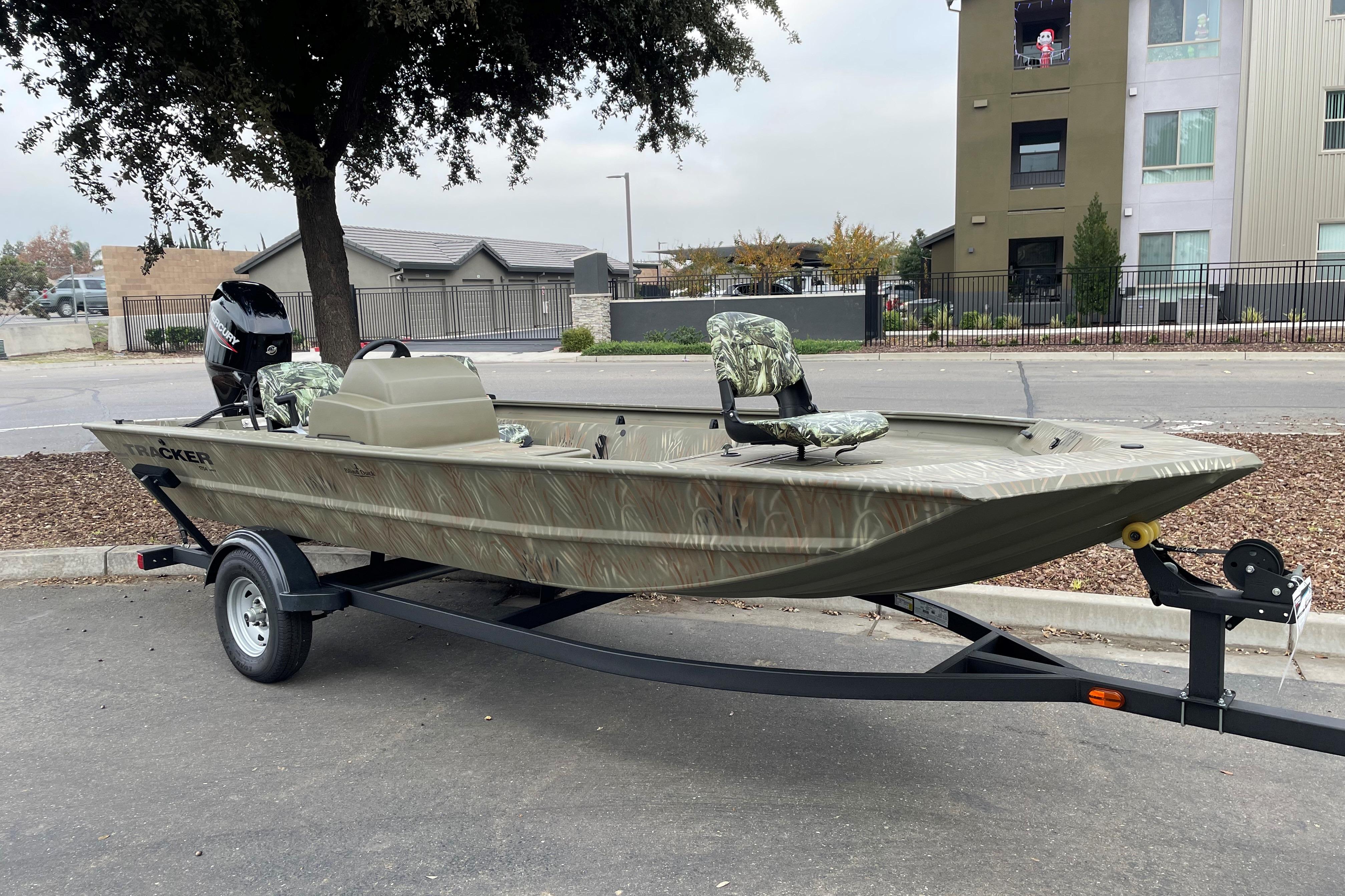 2025 Tracker Grizzly 1754 SC boat on trailer, parked outdoors near buildings.