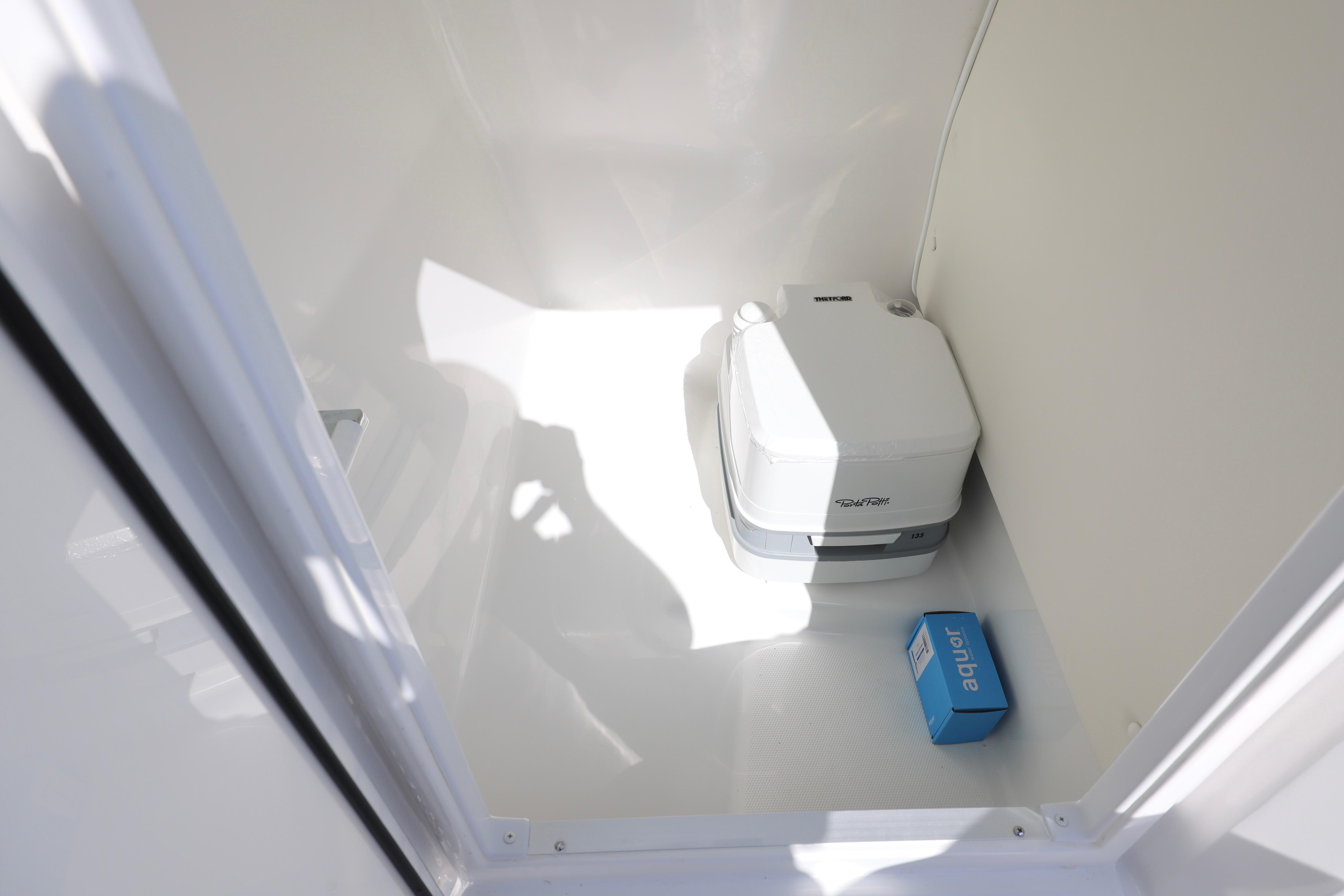2026 Hurricane SunDeck 235 OB boat interior with portable toilet and storage space.