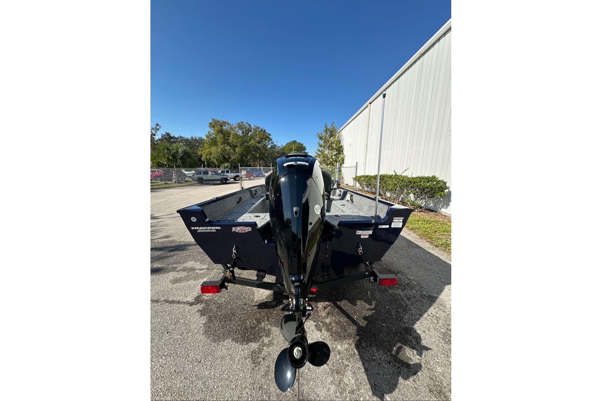 2026 Tracker Pro Guide V-16 SC boat, rear view, parked outdoors on a sunny day.