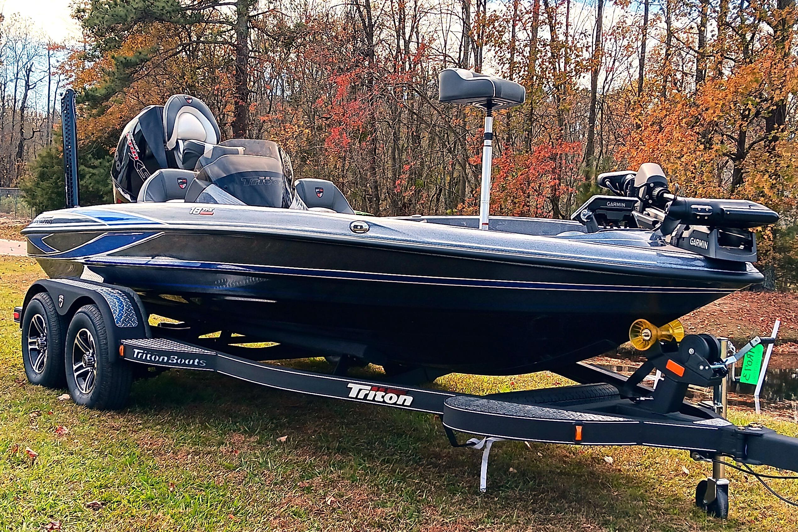 2026 Triton 18 TrX boat on trailer, surrounded by autumn trees.