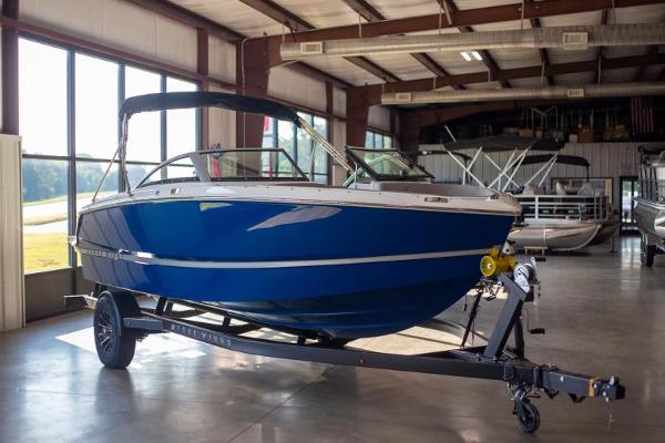 2025 Four Winns H1 boat in showroom, blue hull, on trailer.