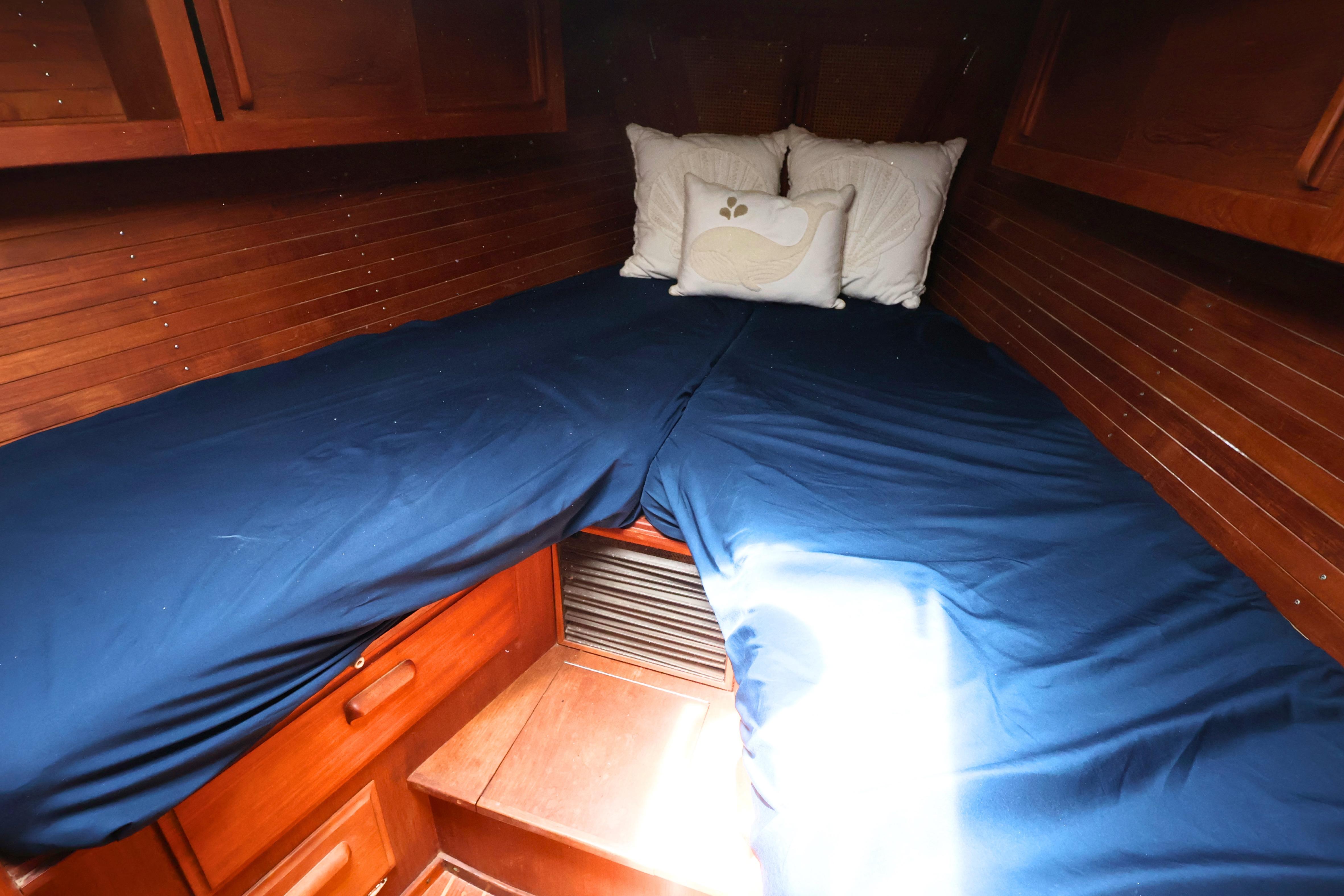 Cozy cabin interior of 1989 J Boat J 40 with blue bedding and wooden finish.