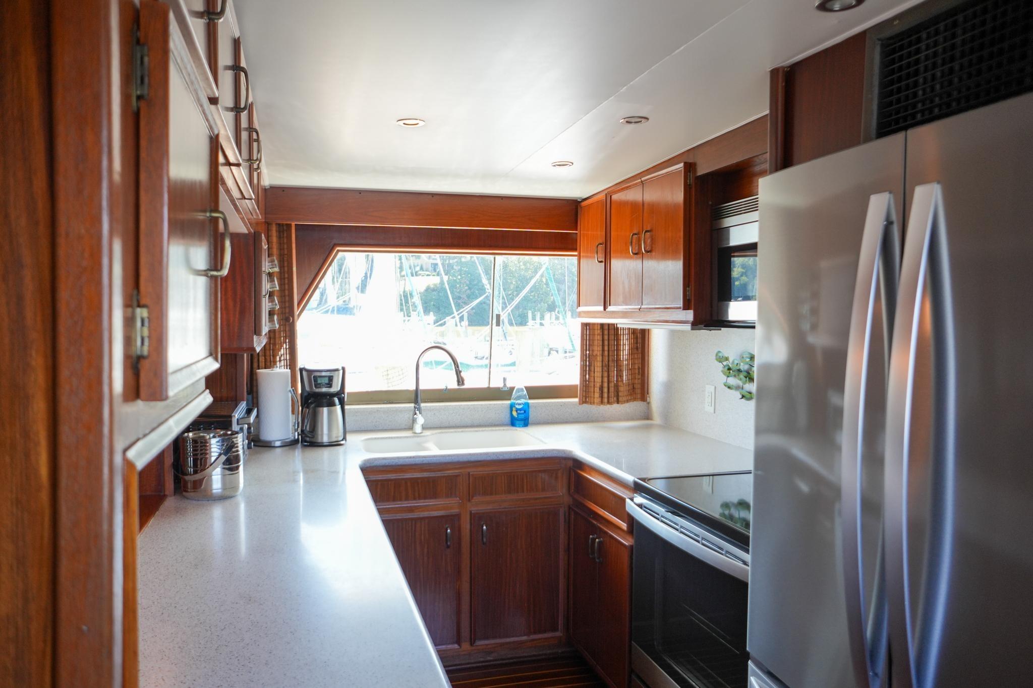 Interior kitchen of 1980 Hatteras 70 Motor Yacht with wooden cabinets and modern appliances.