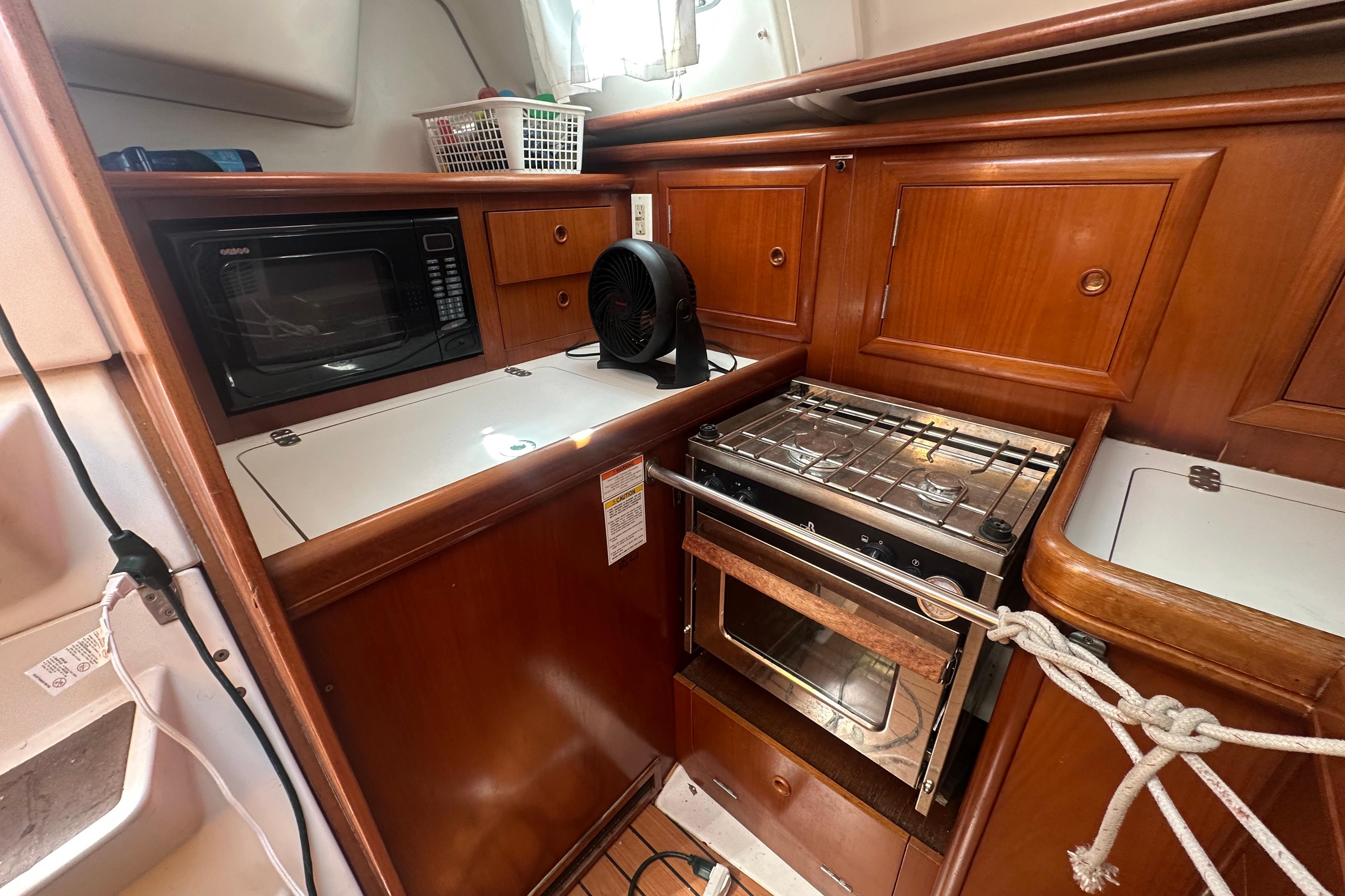 2003 Beneteau Oceanis Clipper 331 yacht kitchen with microwave, stove, and wooden cabinetry.