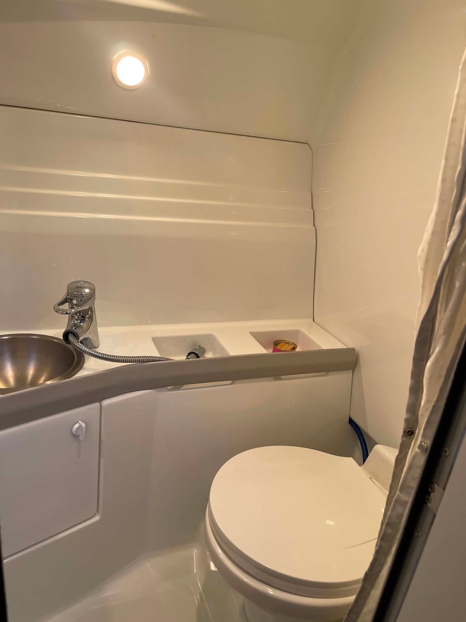 The image shows a clean, modern boat bathroom with a sink and toilet.