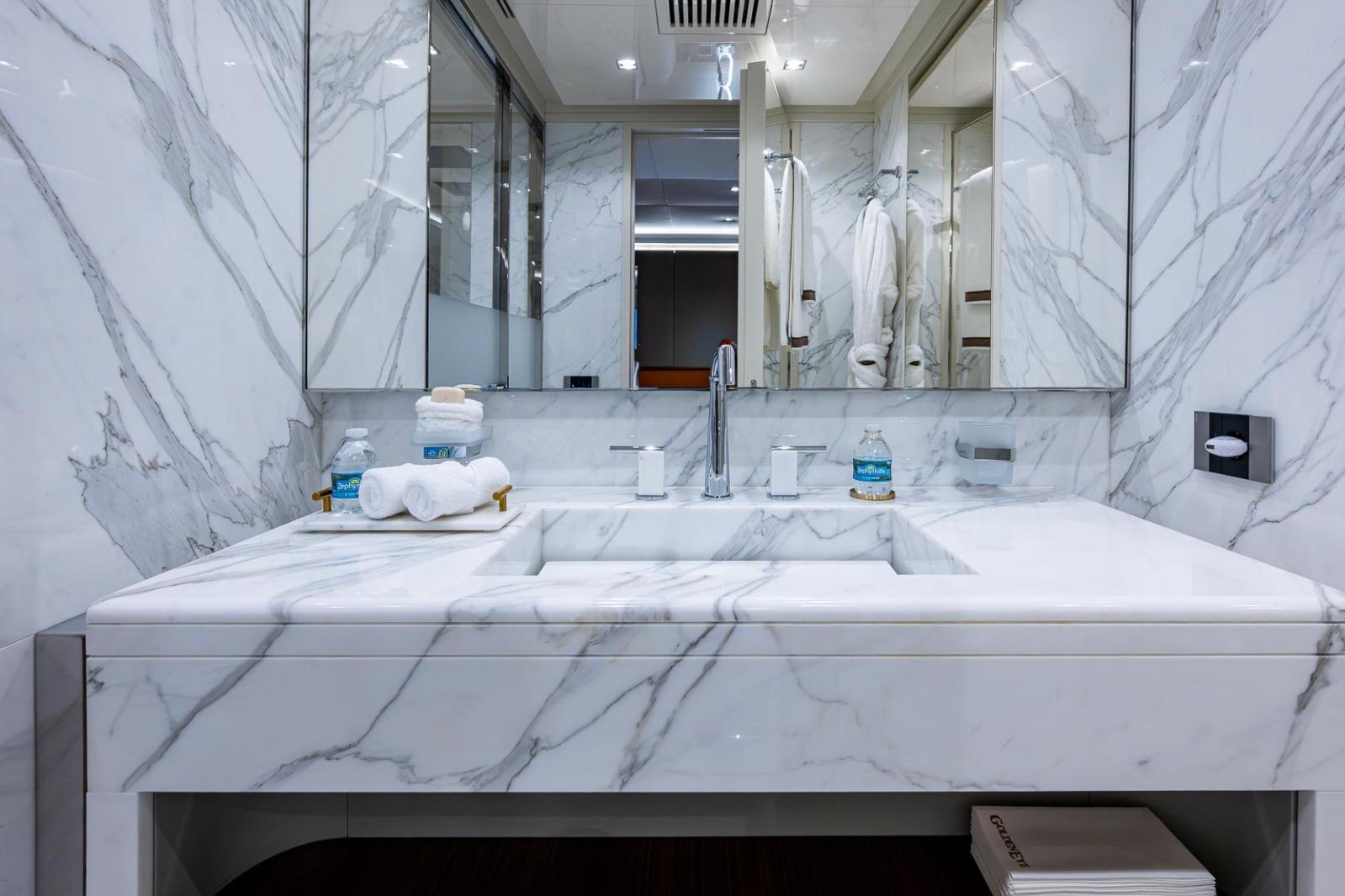 Luxurious marble bathroom in 2020 Overmarine Gransport 54 yacht, featuring elegant fixtures and amenities.