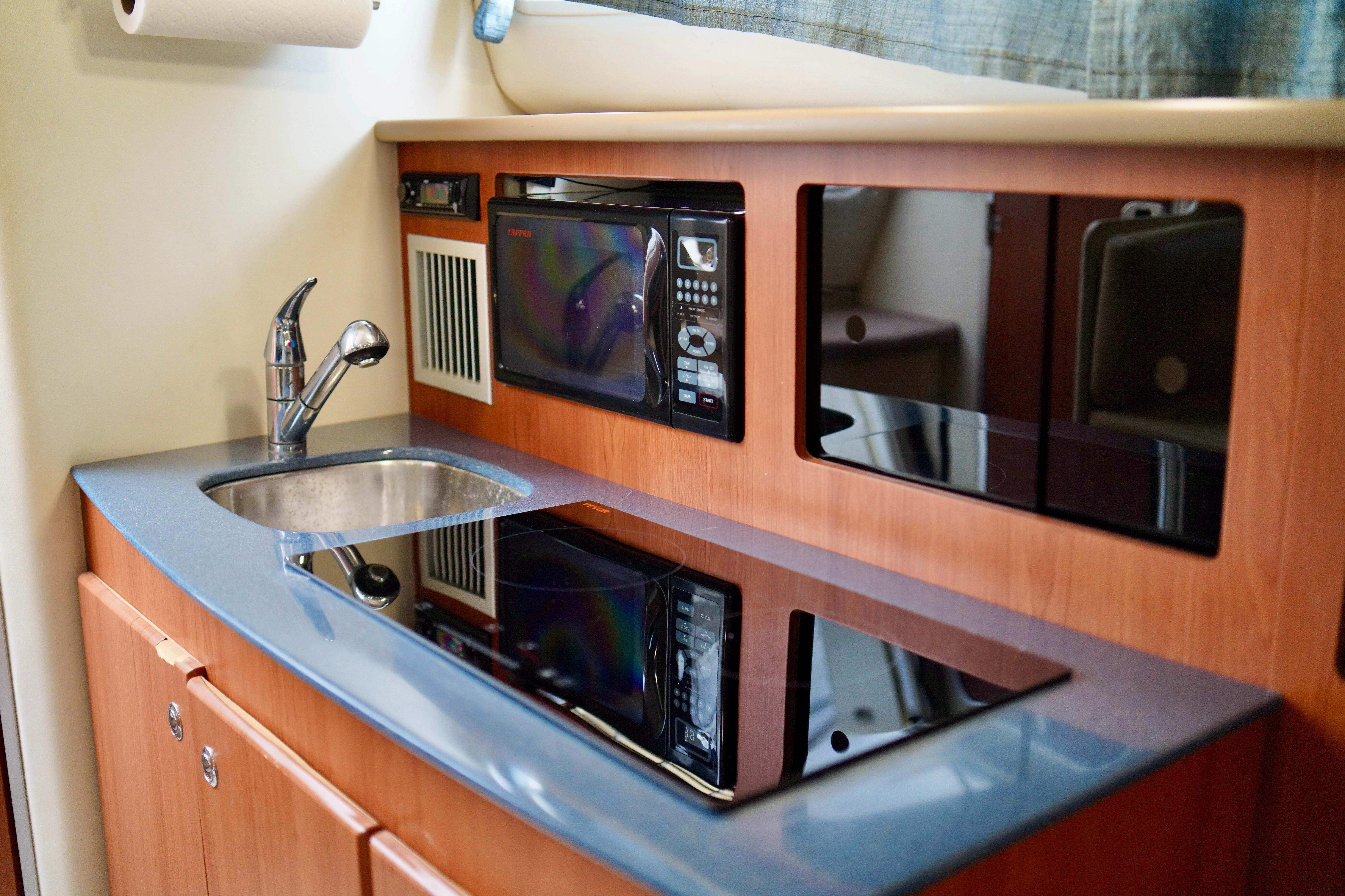 2006 Bayliner 285 boat kitchen with sink, microwave, and stove.