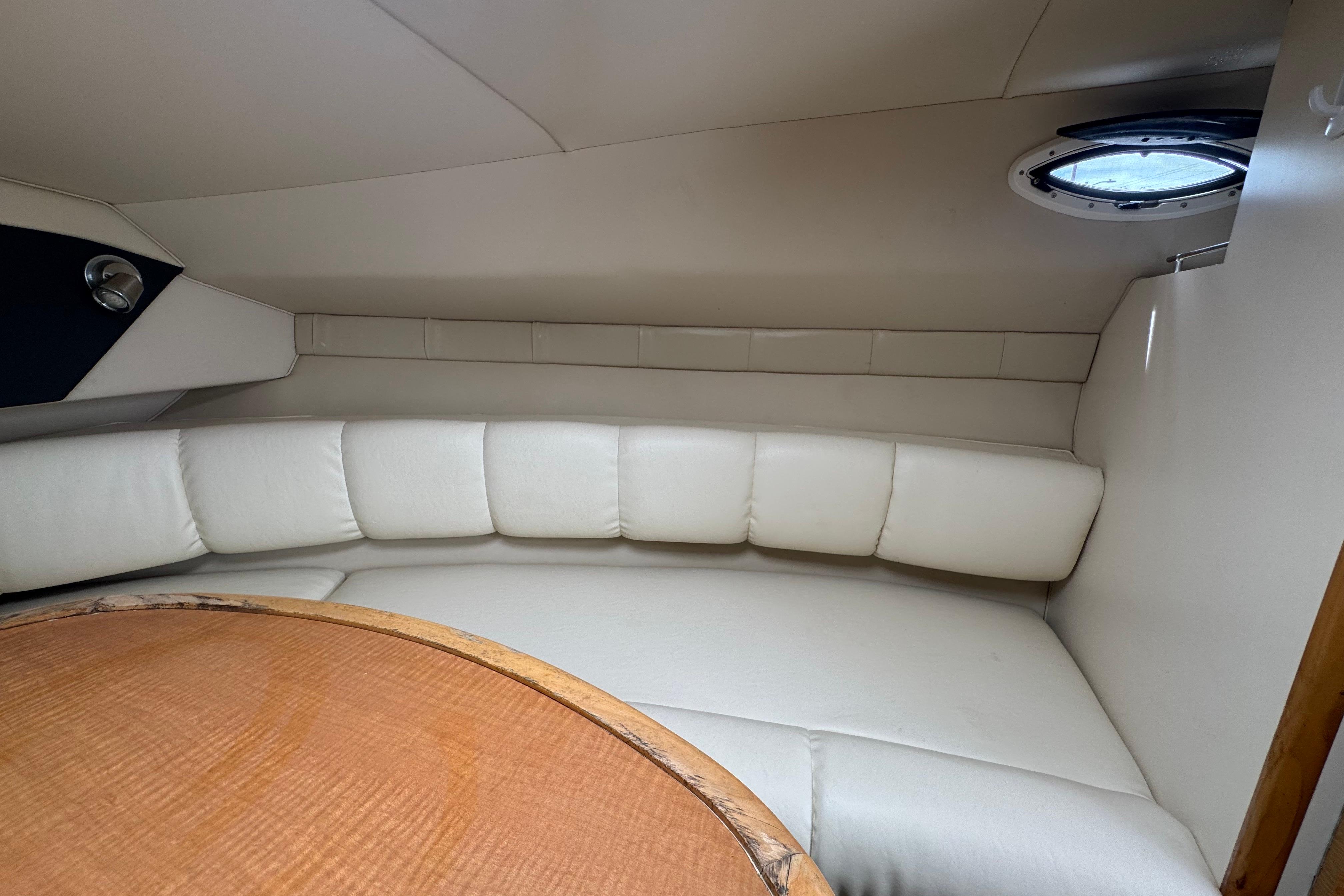 Interior of 2008 Larson Cabrio 260 boat with white leather seating and wooden table.