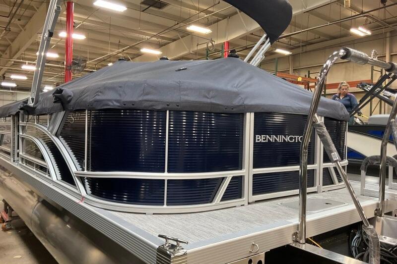 2026 Bennington 22 SSRSF pontoon boat in a showroom, covered and ready for display.