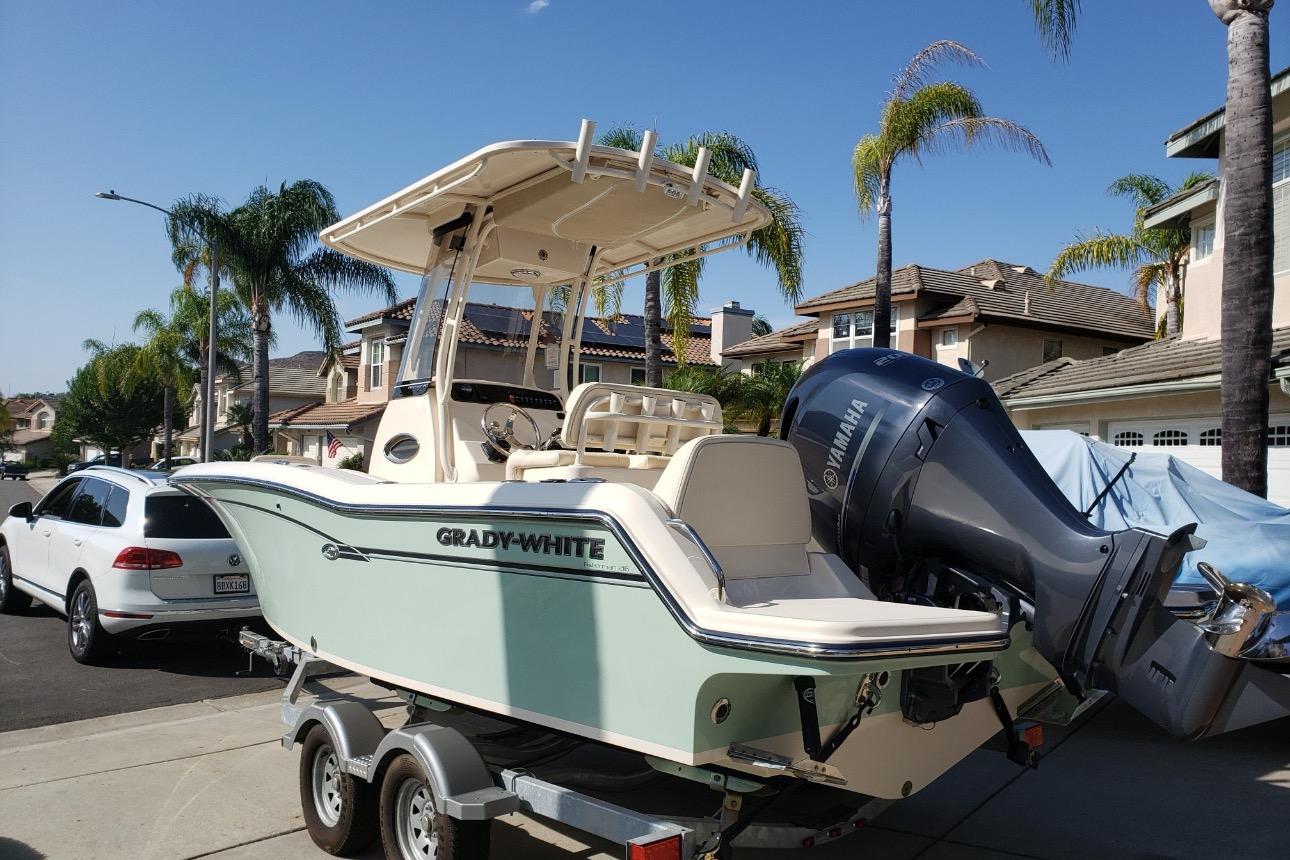 2018 Grady-White Fisherman 216 boat on trailer, parked in suburban neighborhood.