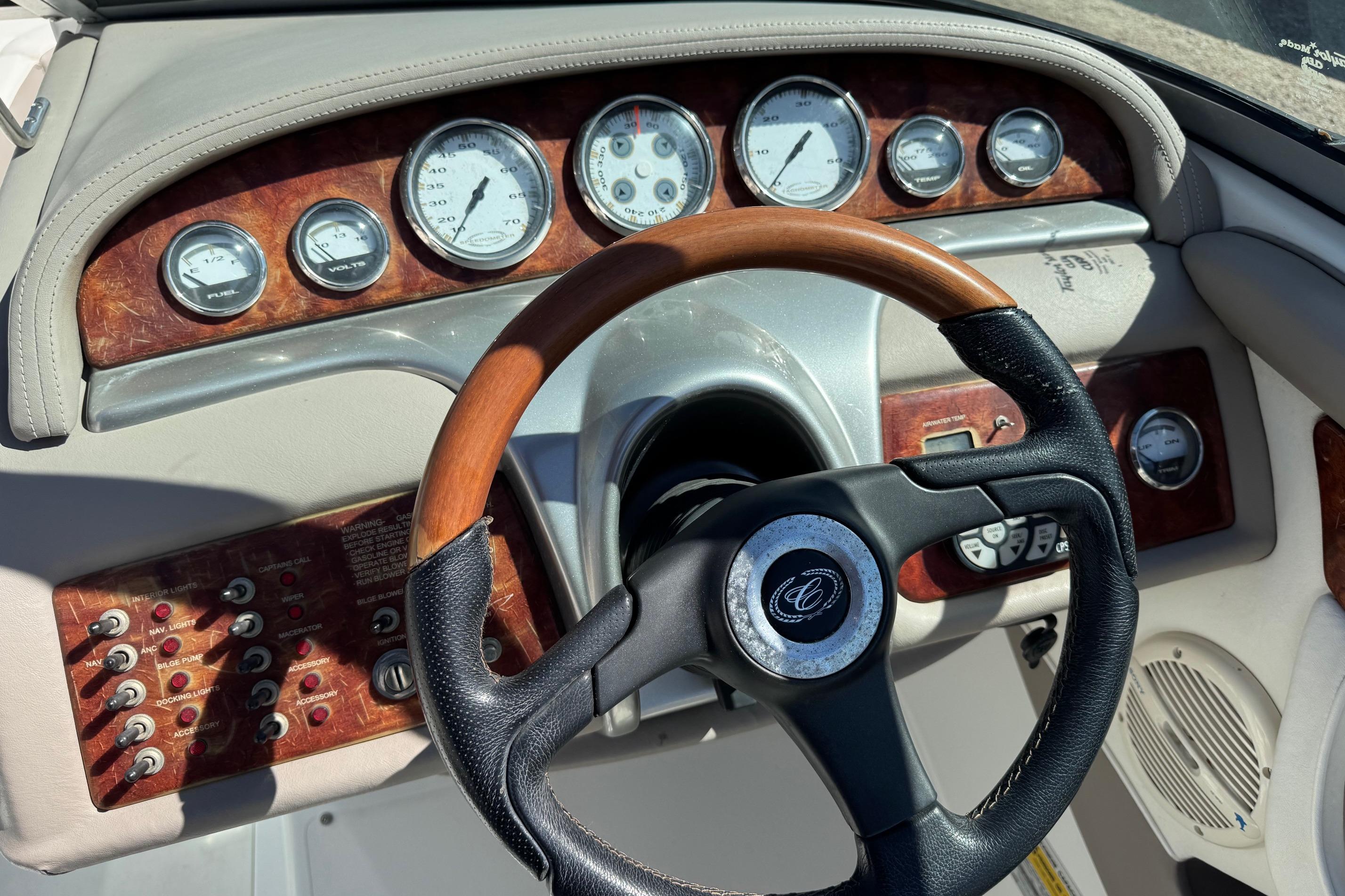 Steering wheel and dashboard of a 2005 Cobalt 240 boat with wood accents.