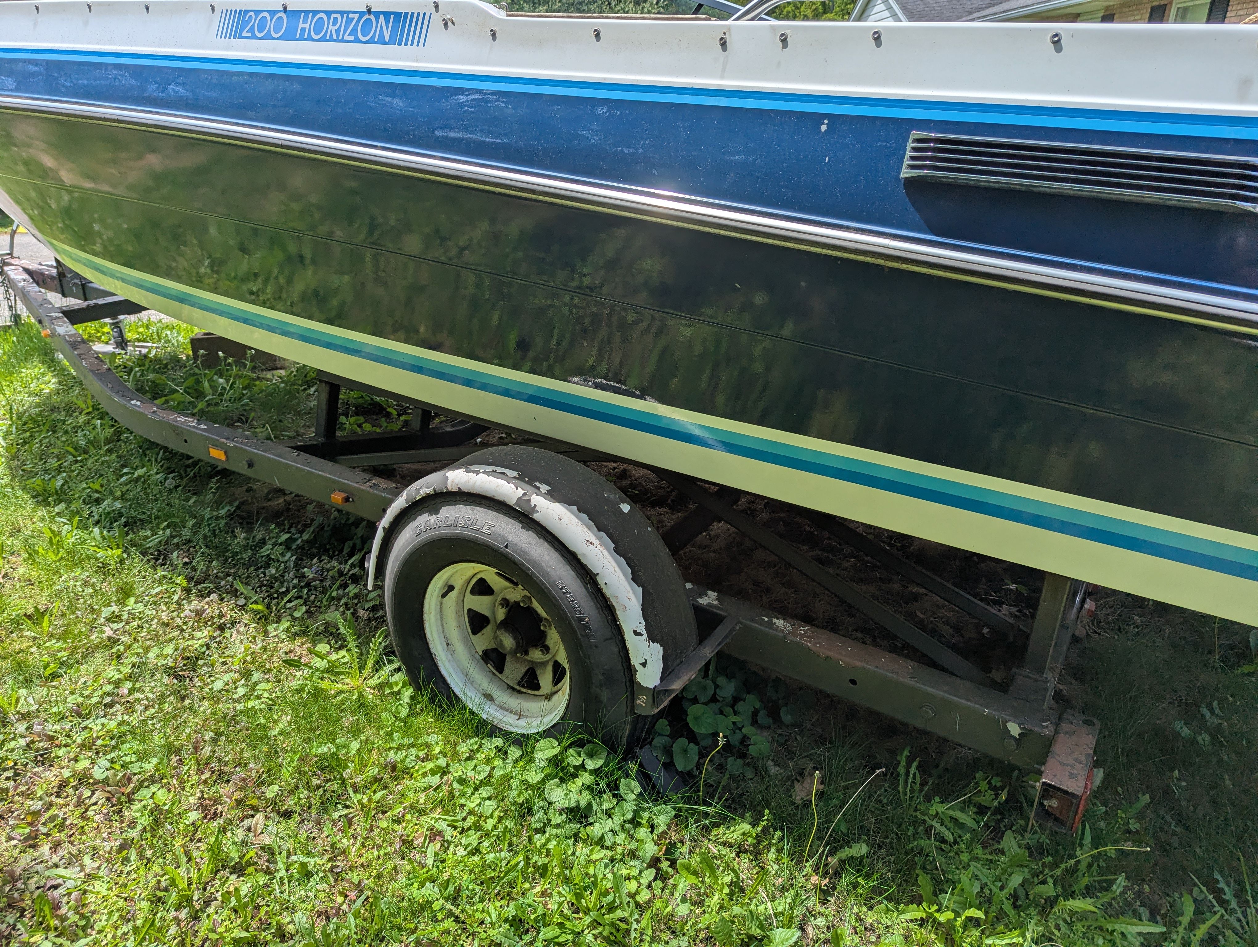 1988 Four Winns 200 Horizon boat on trailer in grass.