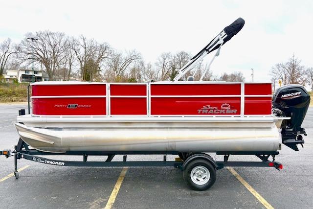 2026 Sun Tracker Party Barge 18 DLX pontoon boat on trailer, red and silver design.