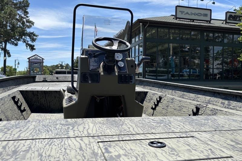 2026 Tracker Grizzly 2072 CC boat with camouflage design, parked near a showroom.