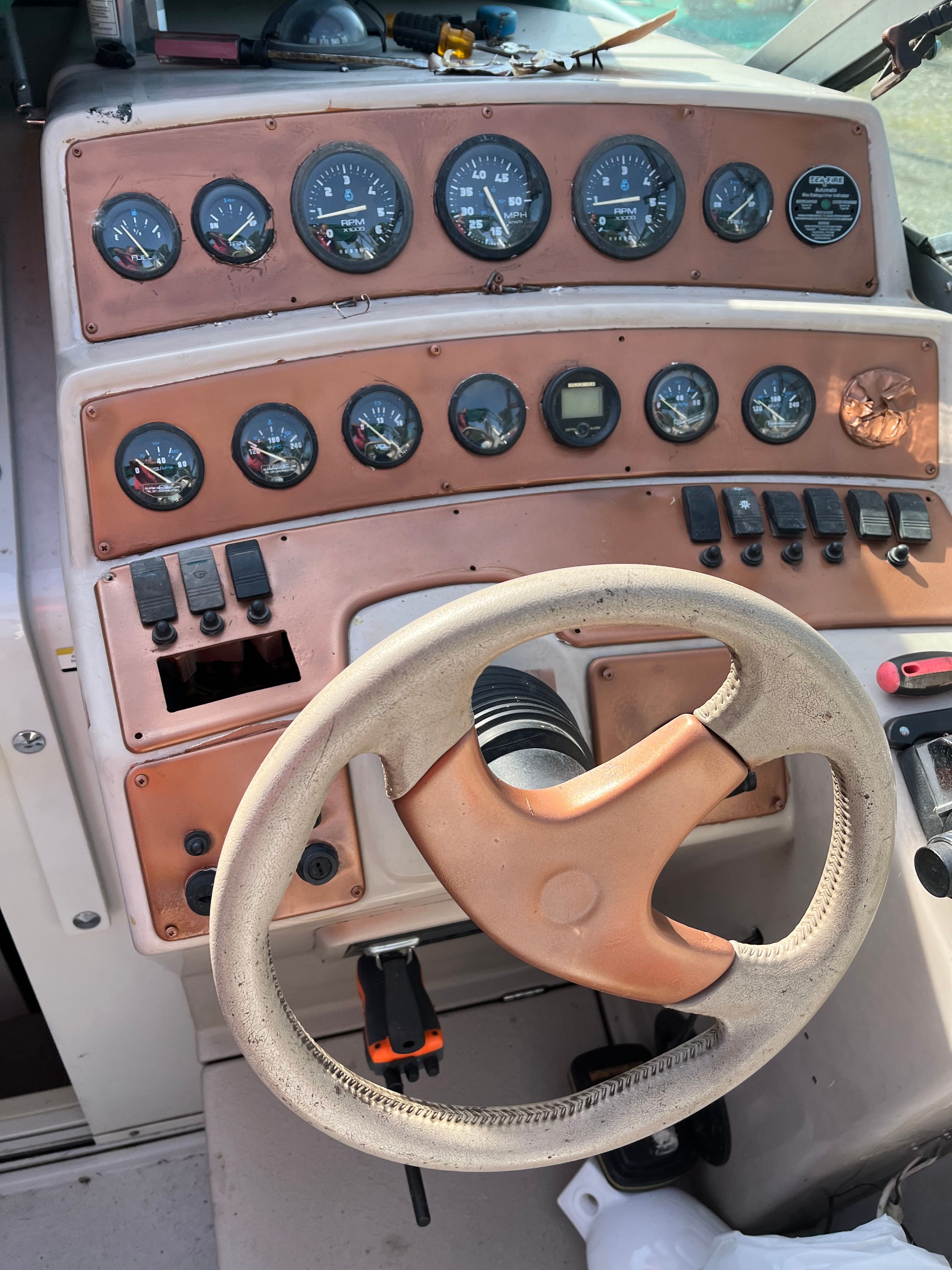 Boat dashboard with numerous gauges and a steering wheel.