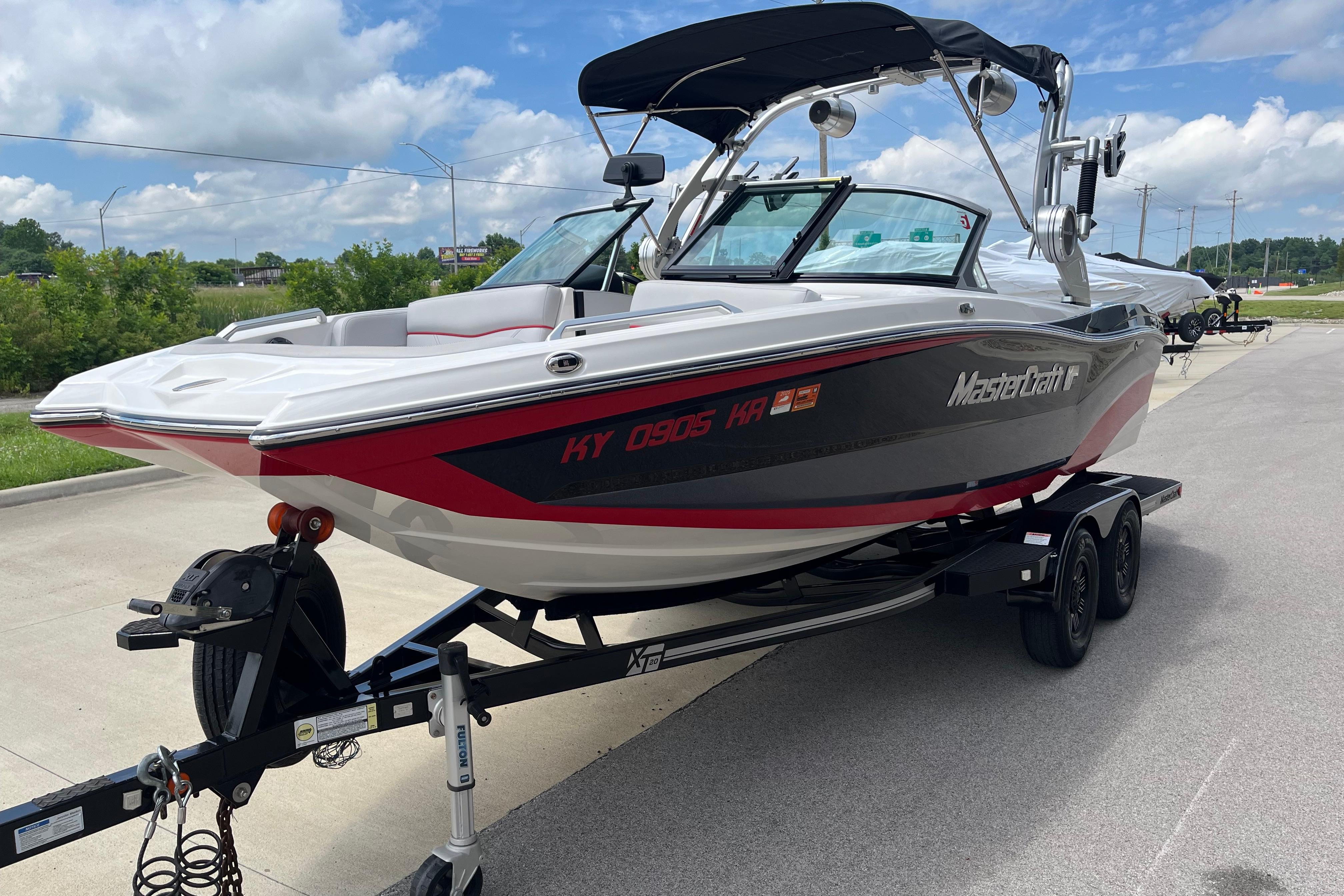 2019 MasterCraft XT20 boat on trailer, parked outdoors under a cloudy sky.