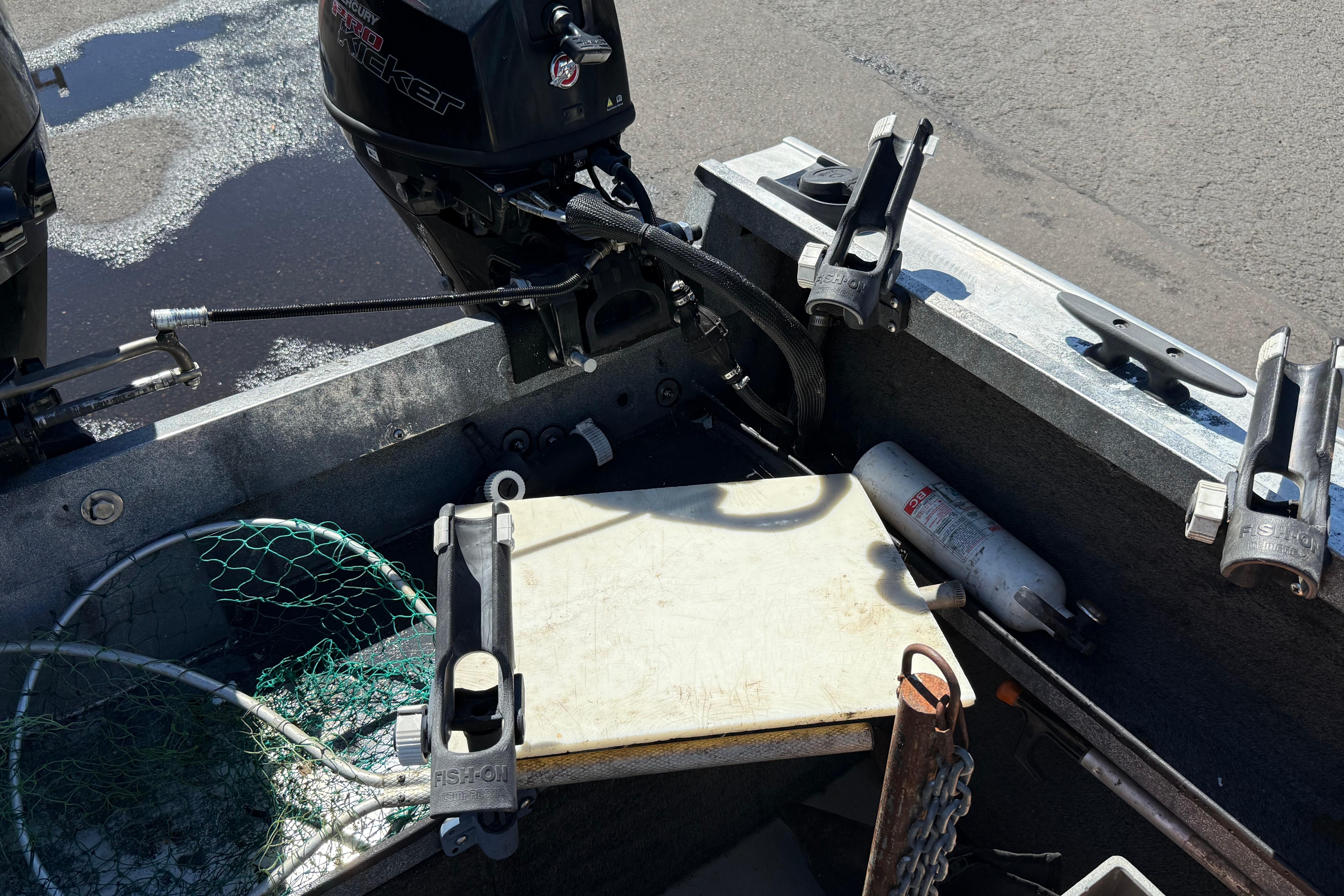 2004 Alumaweld Intruder Outboard 20 boat interior with fishing gear and motor.