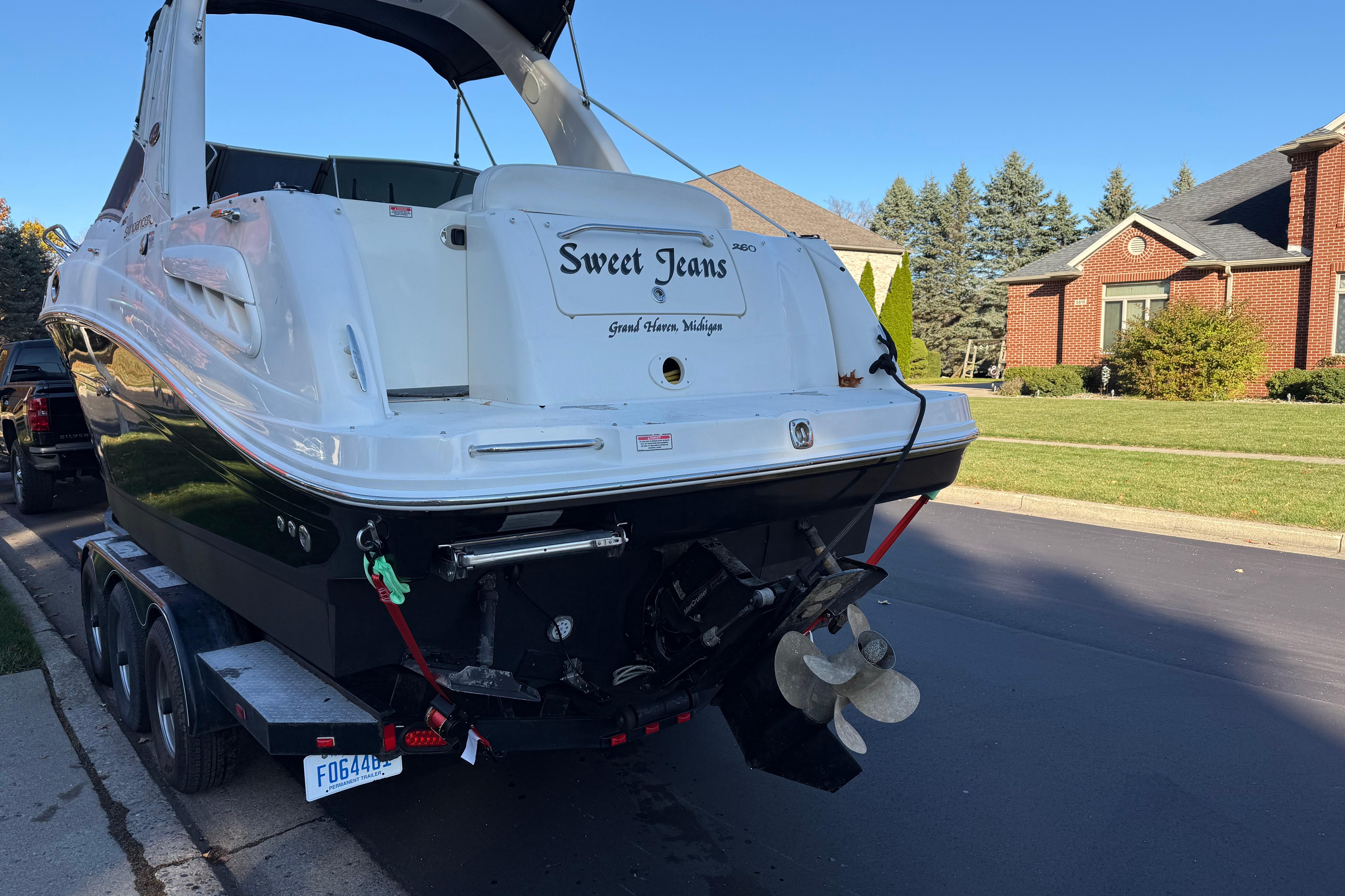2006 Sea Ray 260 Sundancer boat on trailer, parked in suburban neighborhood.