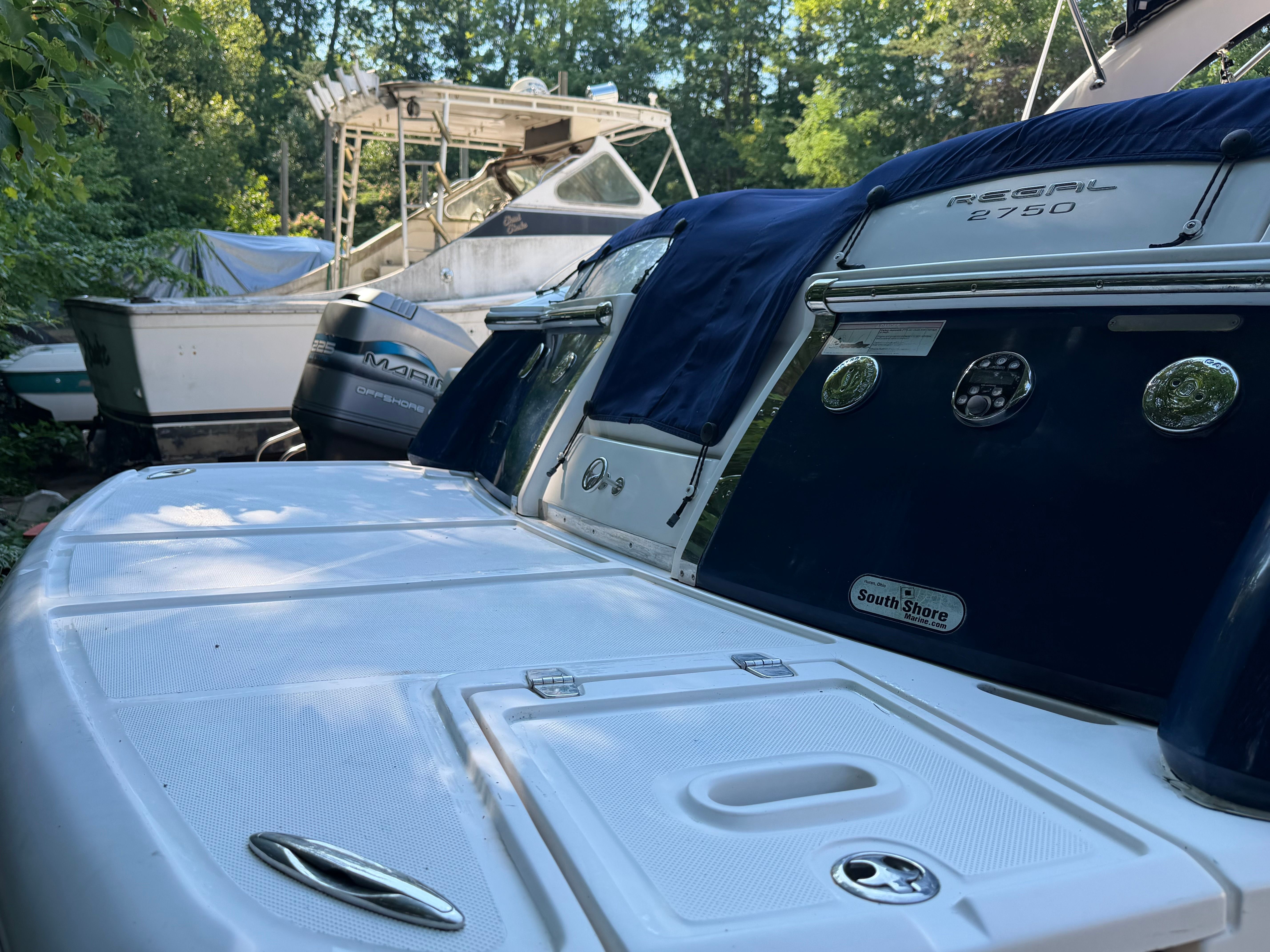 The image shows the stern of a 2011 Regal 2750 Cuddy, surrounded by trees and other boats.