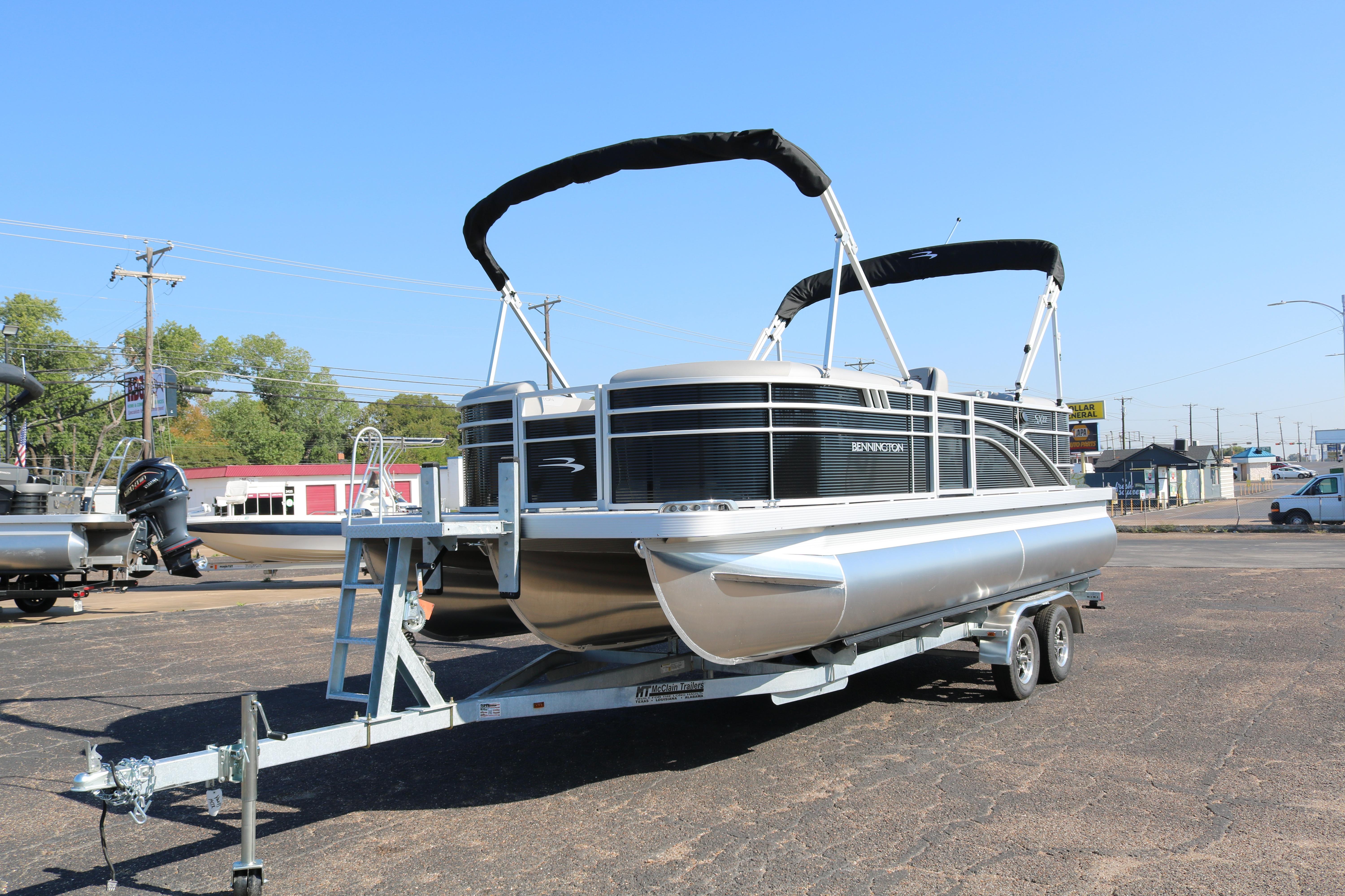 2026 Bennington 22SX Stern Radius pontoon boat on trailer, parked outdoors under clear sky.