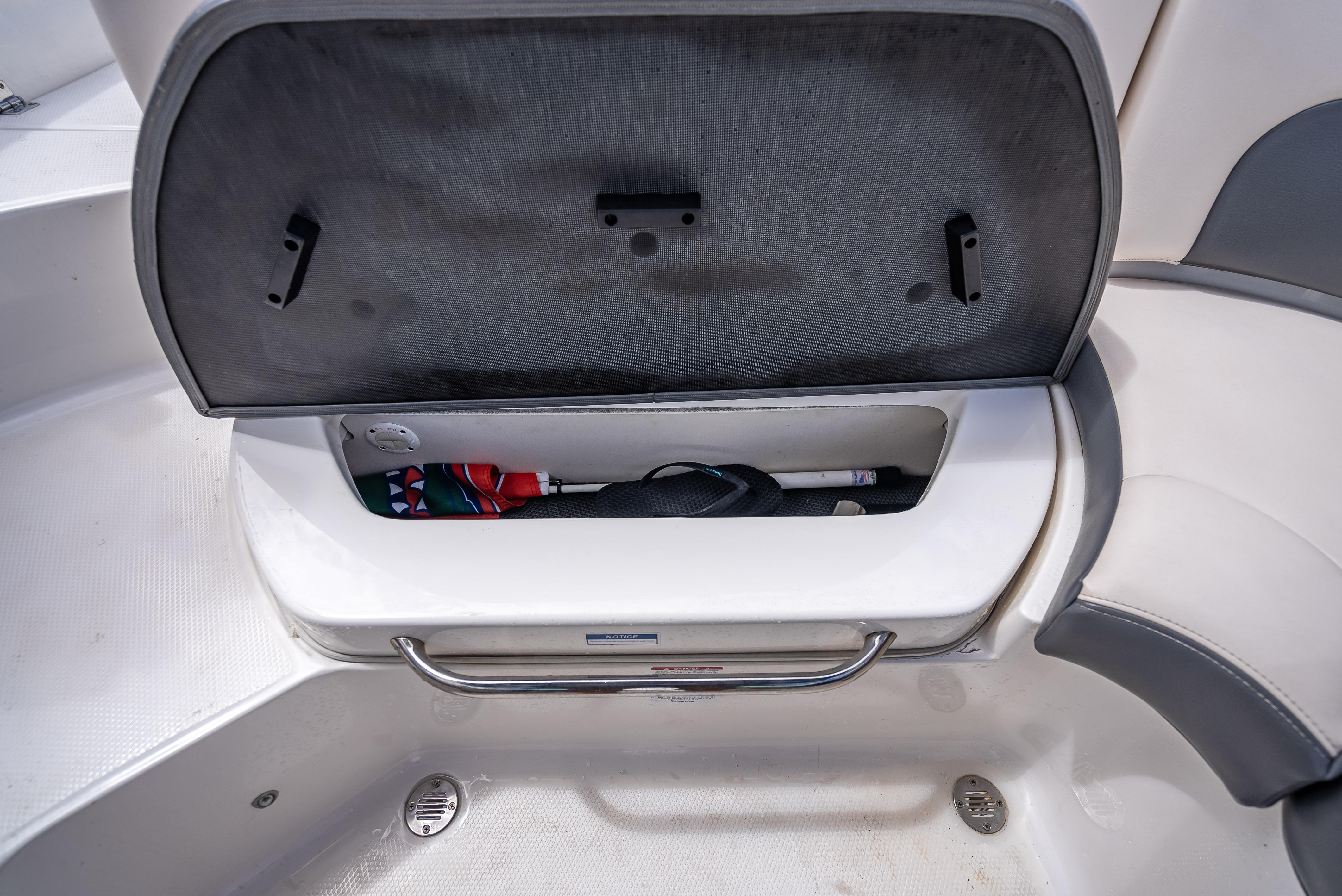 Open storage compartment in 2017 Chaparral 227 SSX boat, showing interior space and items.