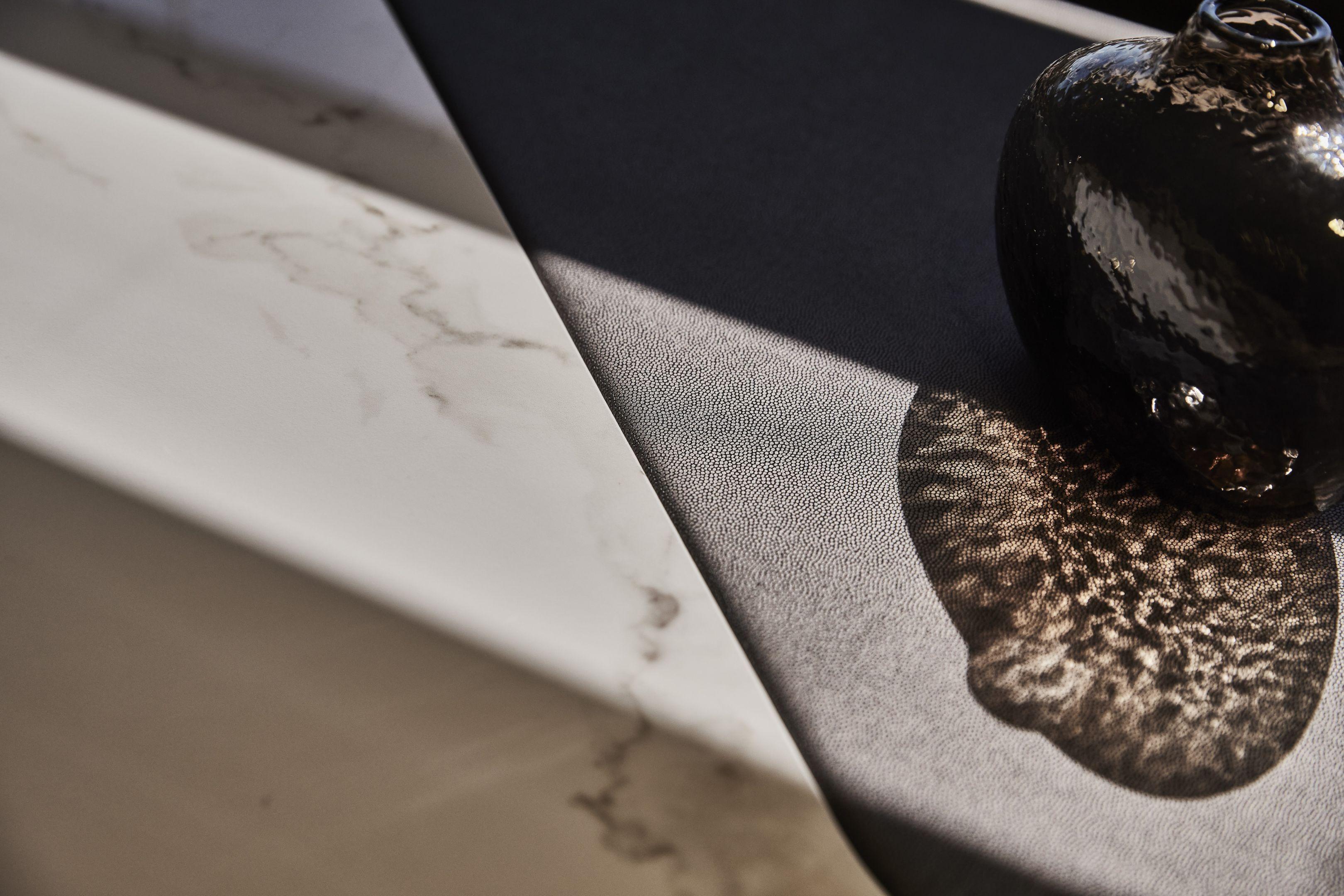 A textured surface with a dark vase casting a shadow, Prestige X60 2026.