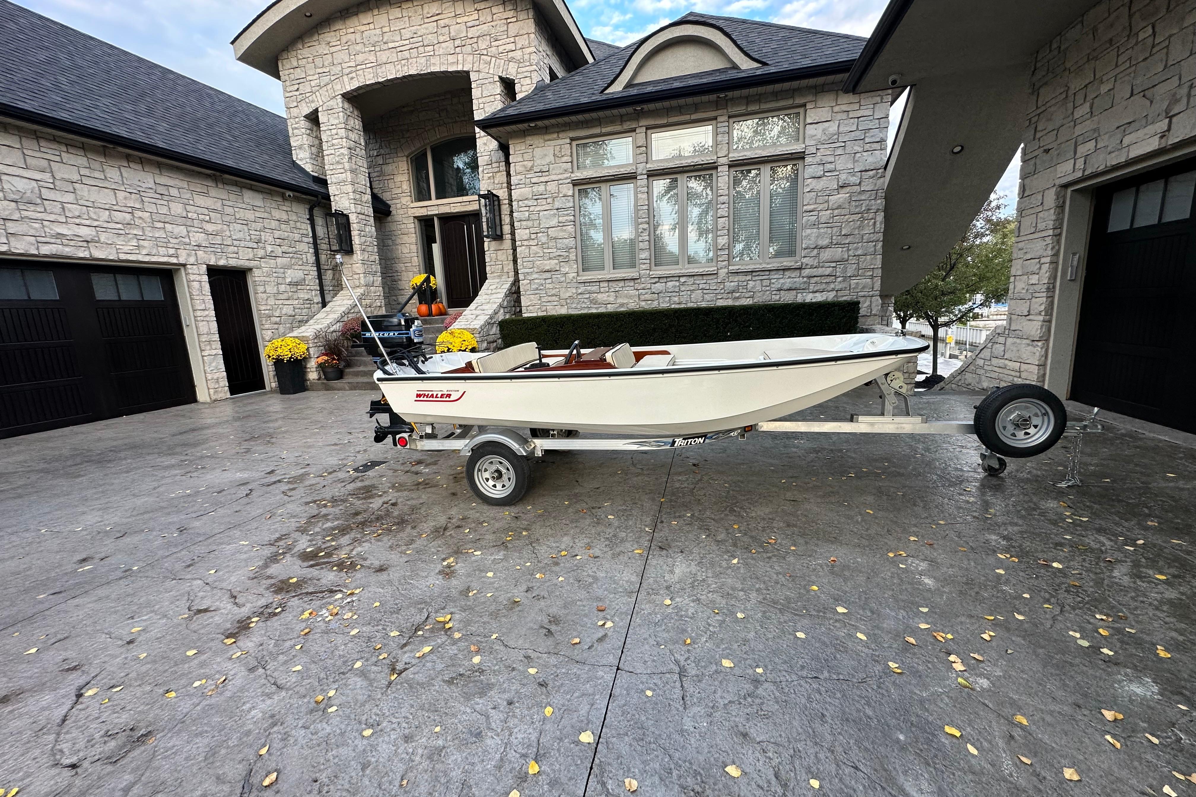 1975 Boston Whaler Classic boat on trailer in front of a stone house.