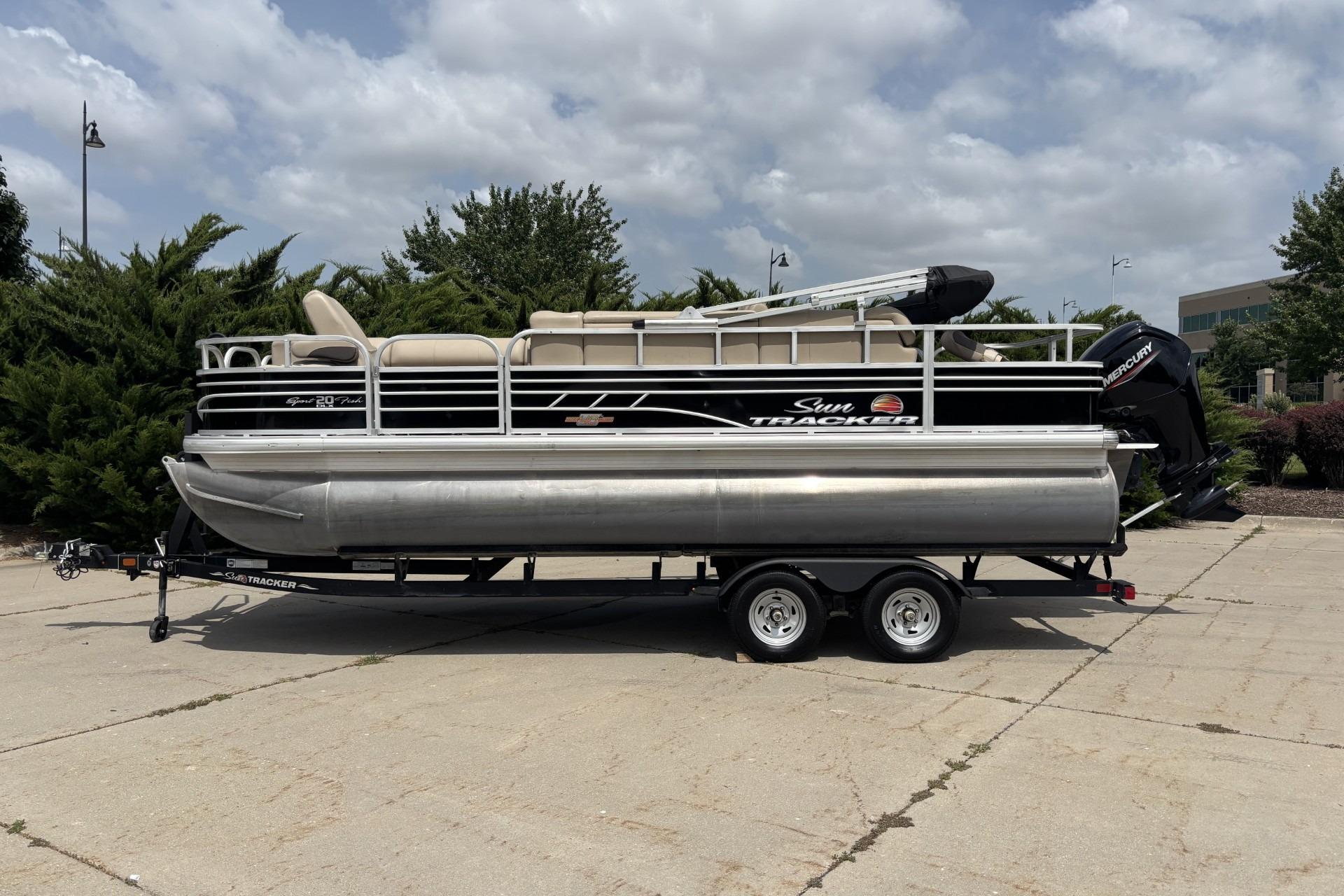 2023 Sun Tracker SportFish 20 DLX pontoon boat on trailer, parked outdoors.