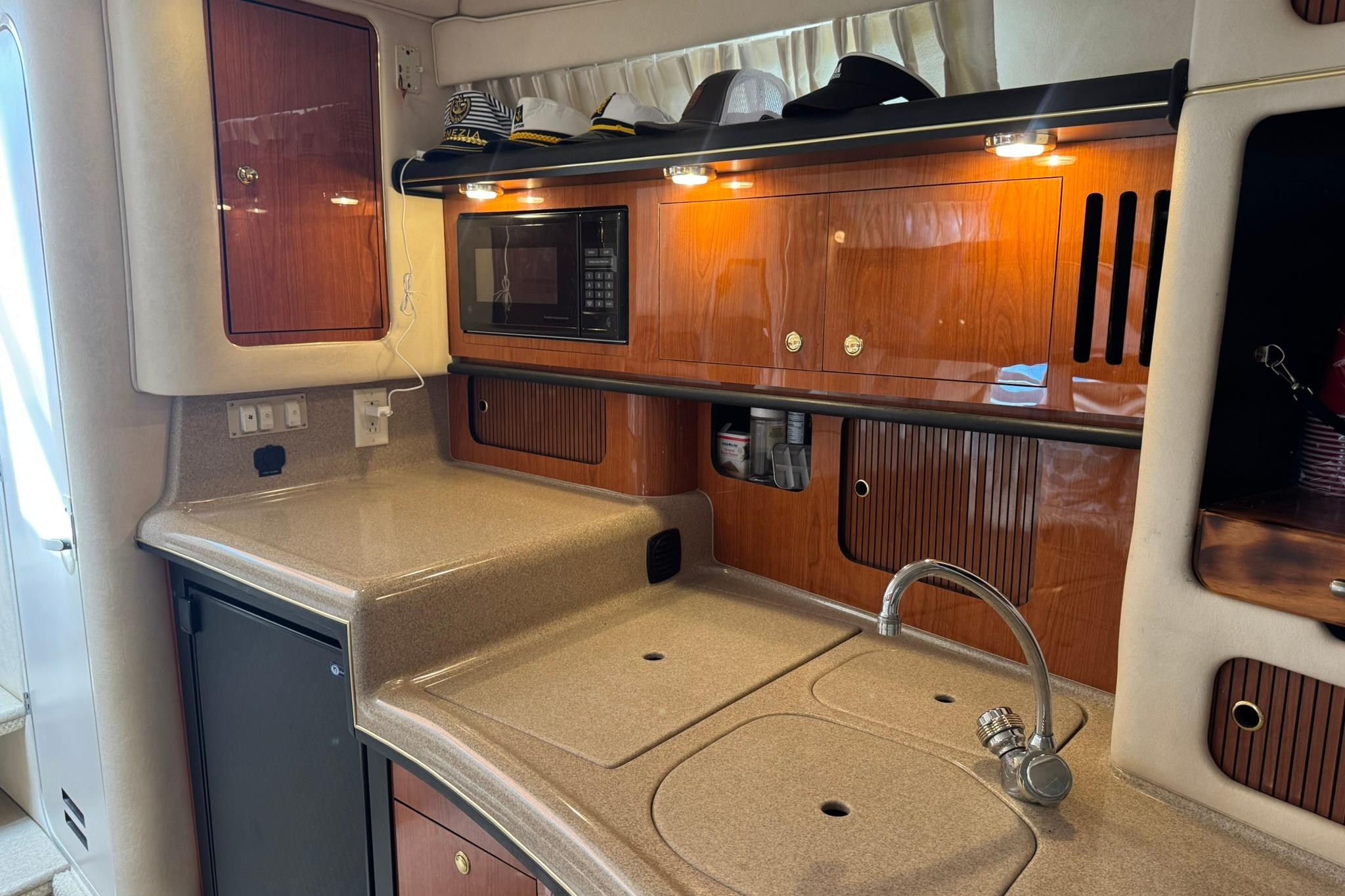 Interior of 2001 Sea Ray 340 Sundancer yacht with kitchenette and wooden cabinetry.