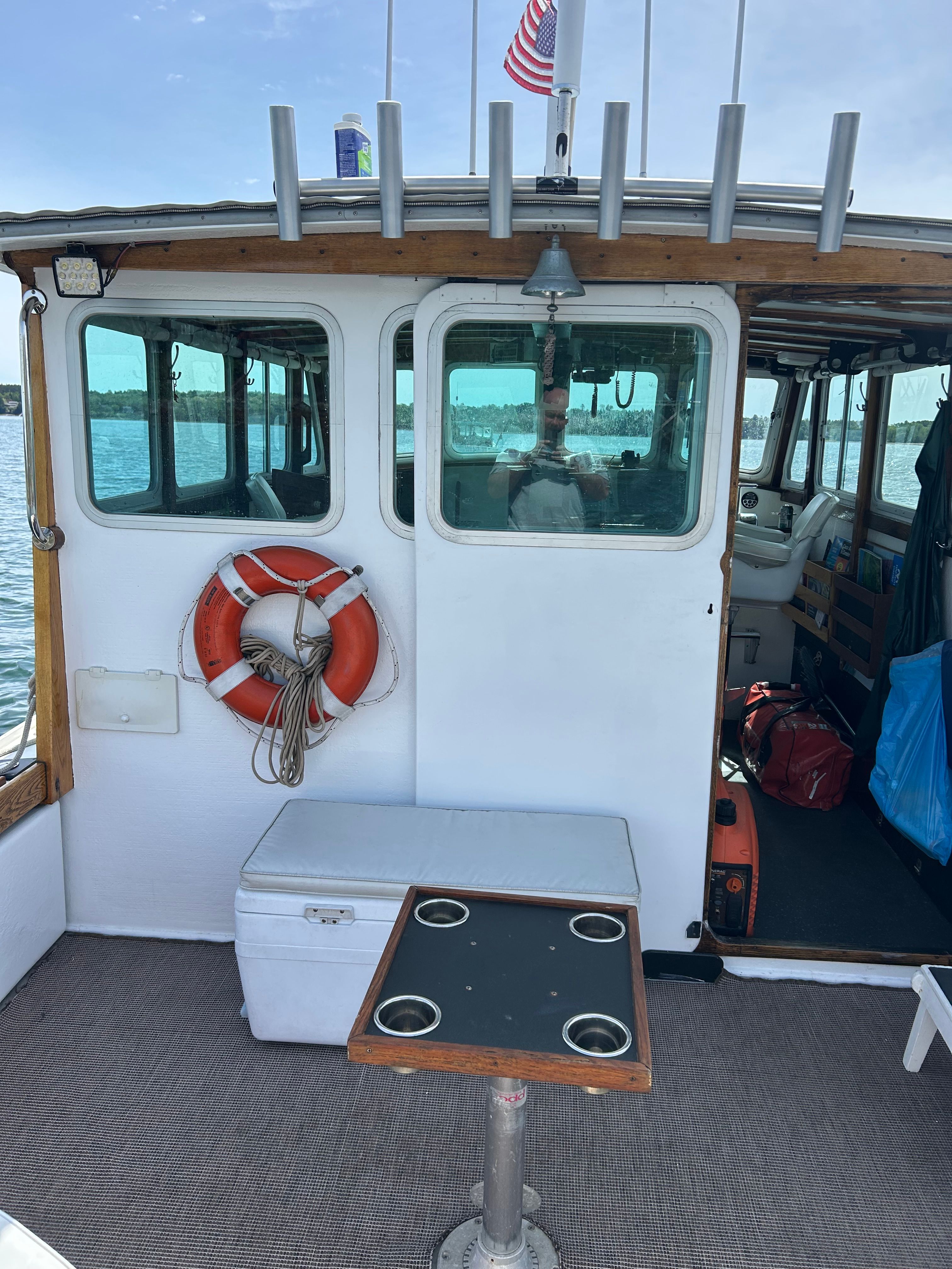 The boat features an open cabin with a table and a life ring on the wall.