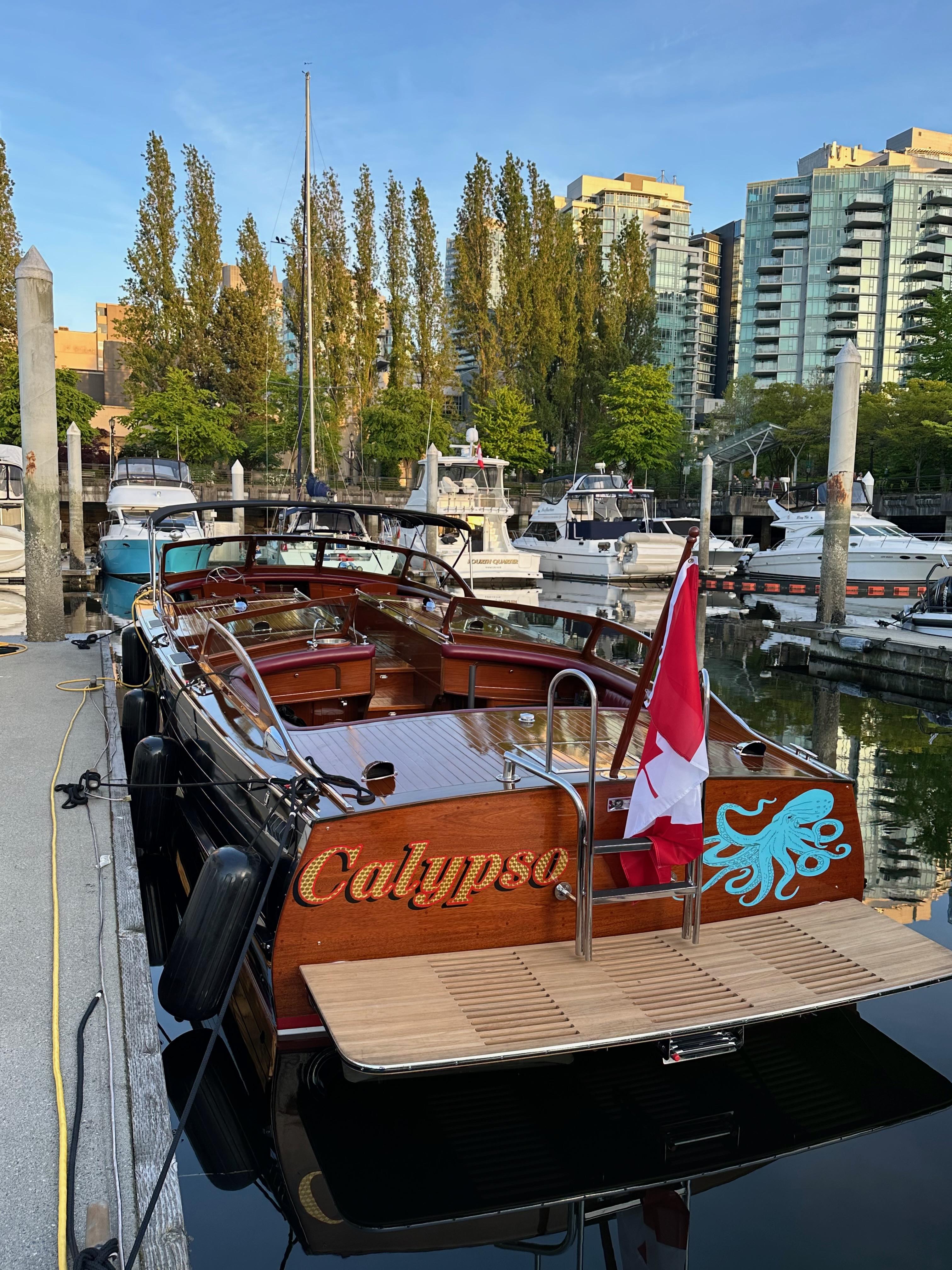 1946 Stephens Triple Cockpit boat "Calypso" docked, featuring a Canadian flag and waterfront view.