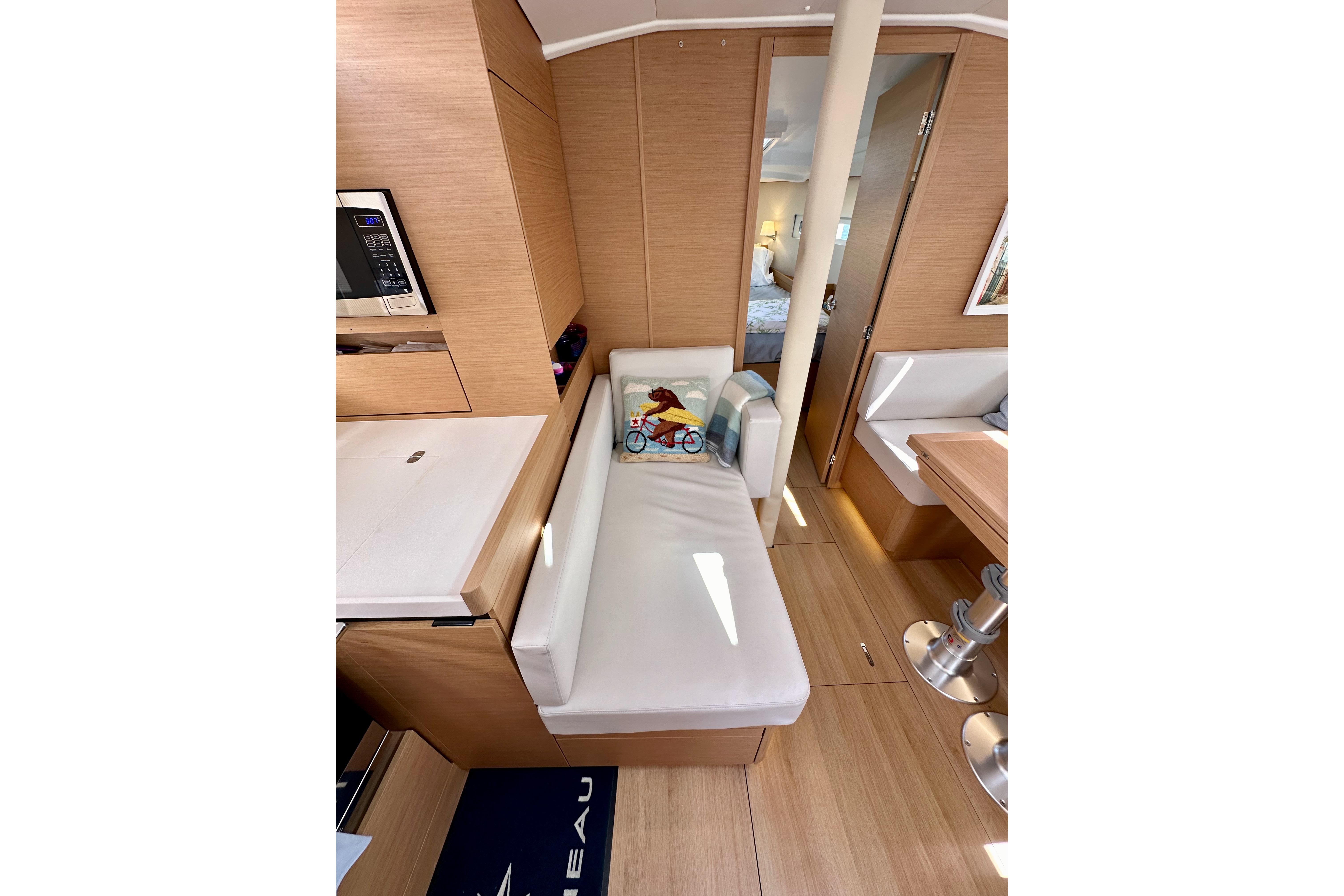 Interior of 2024 Jeanneau Sun Odyssey 410 yacht, featuring modern wood finish and cozy seating.