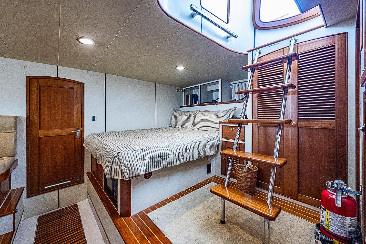 Luxurious cabin interior of 2014 Marlow 80 Explorer yacht with wooden accents and cozy bed.