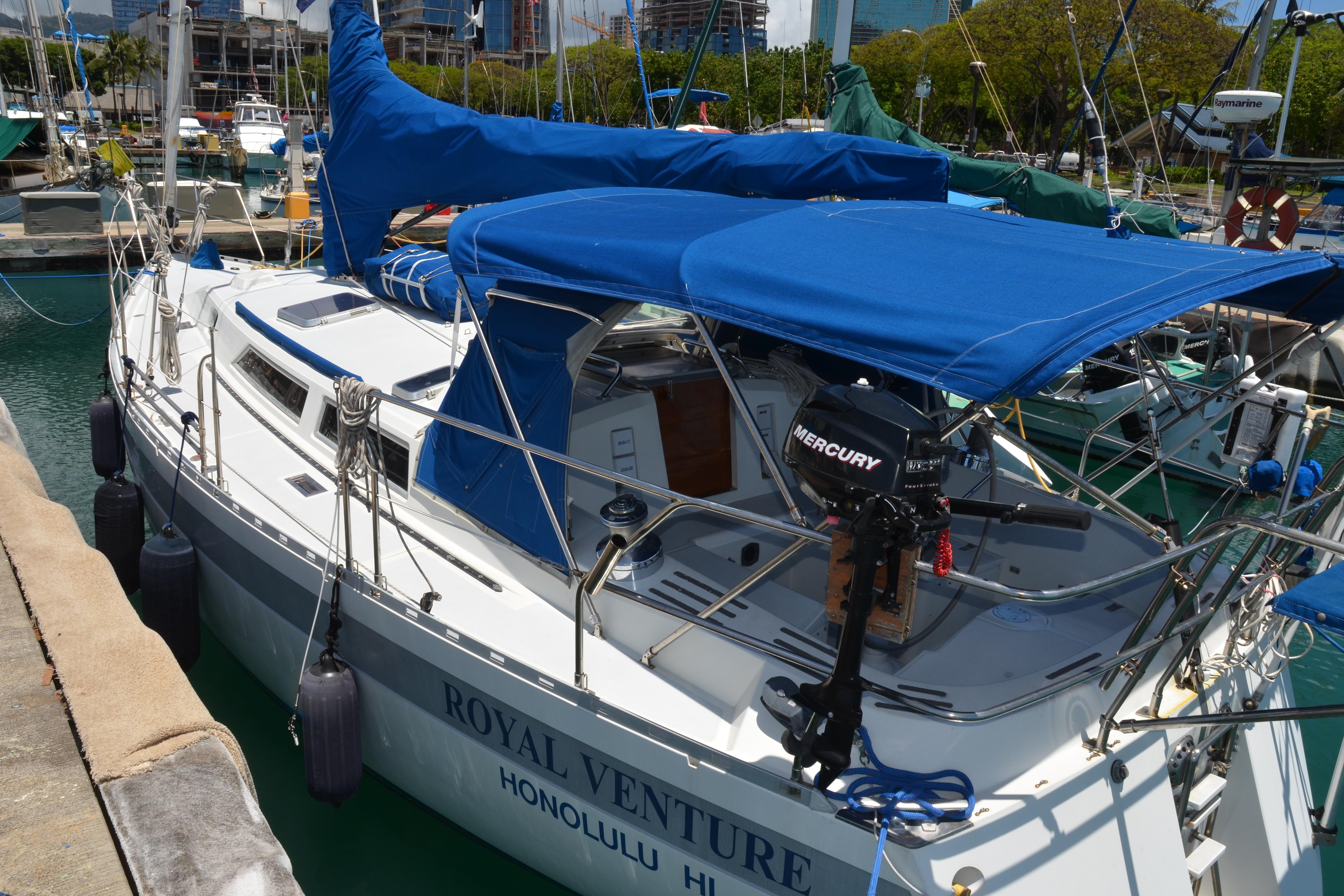 1987 Norseman 400 sailboat docked in marina, featuring blue covers and Mercury outboard motor.
