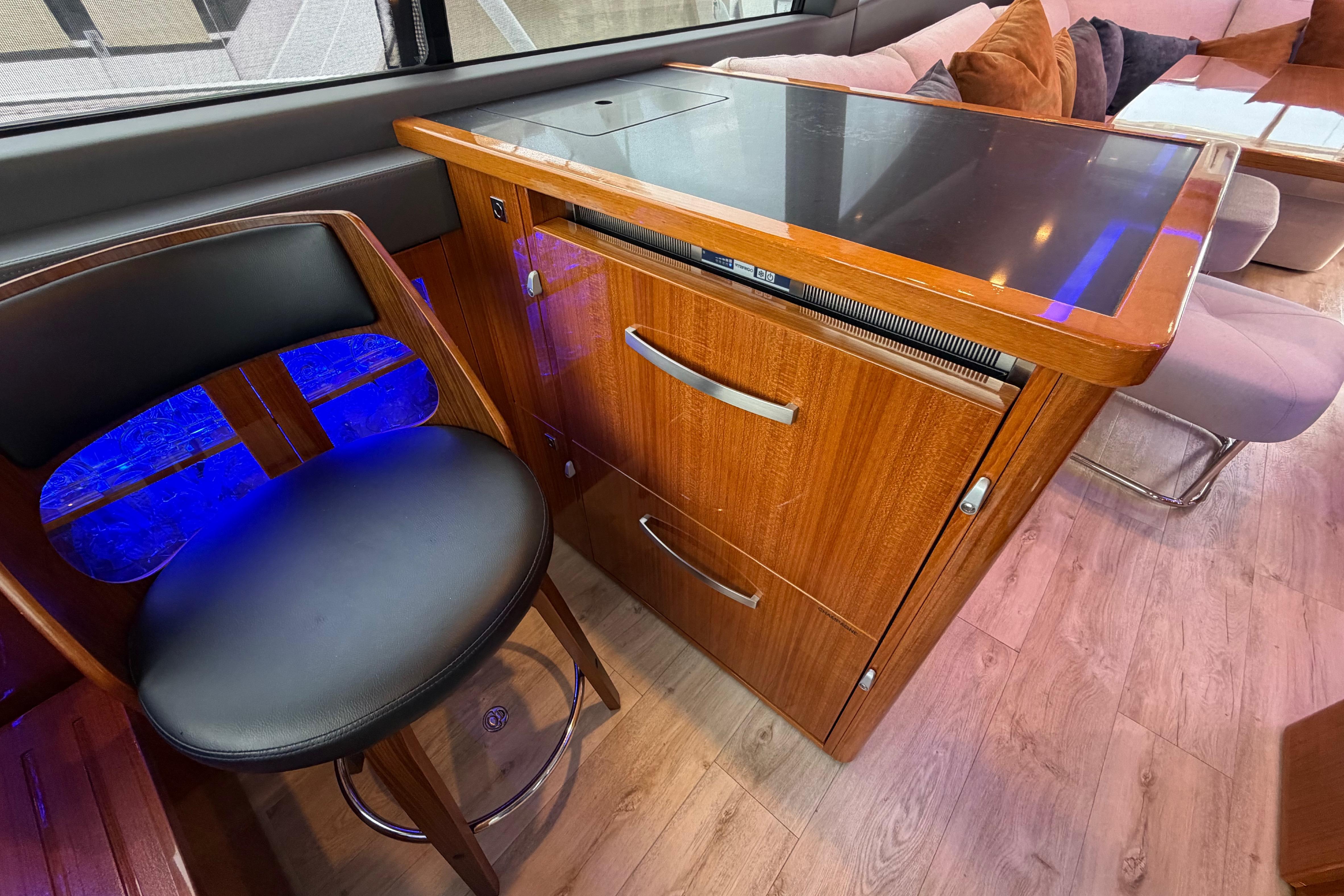 Luxurious interior of 2023 Riviera 645 SUV yacht with sleek wood cabinetry and modern seating.