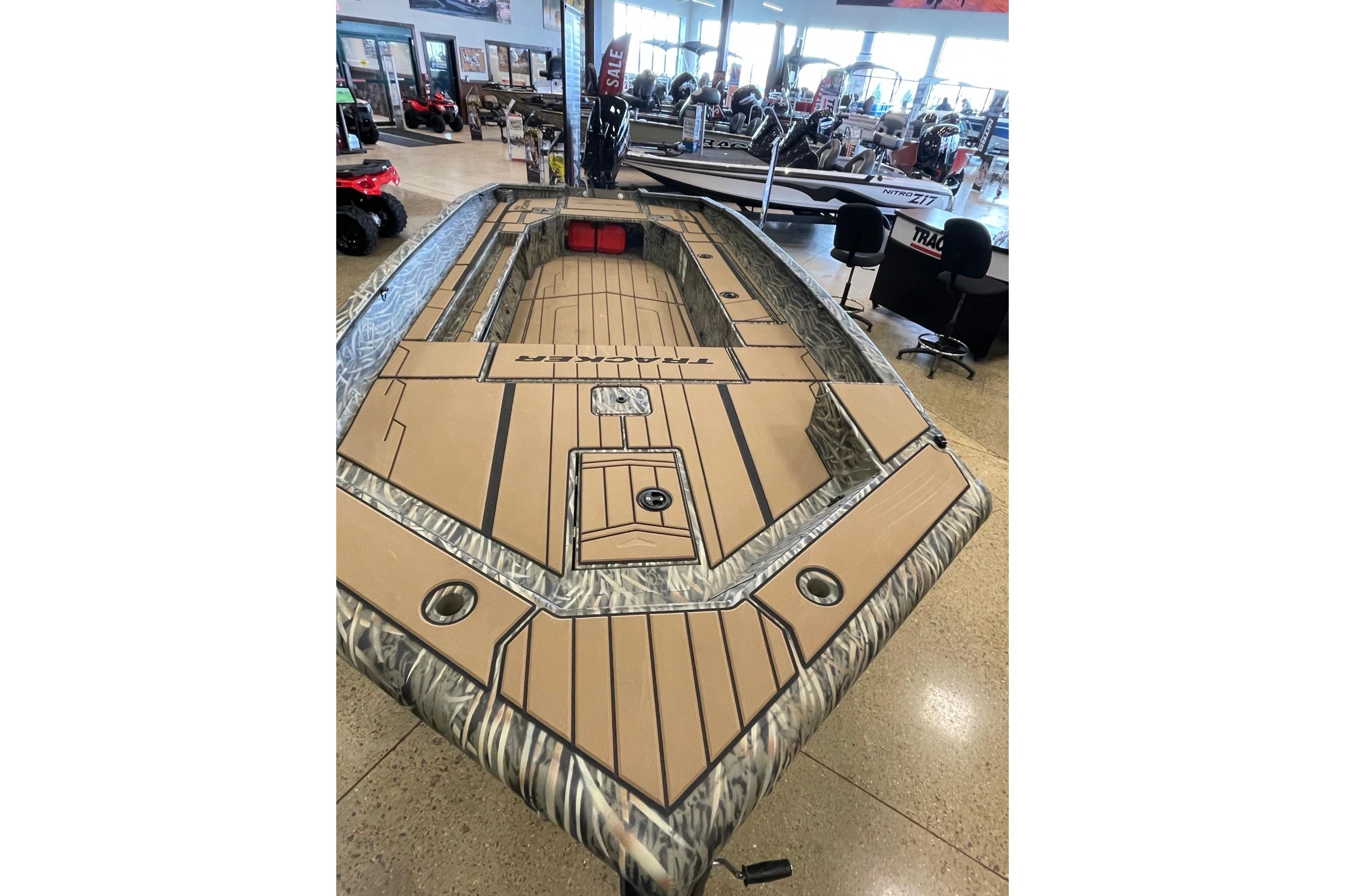 2026 Tracker Grizzly 1756 T Marsh boat displayed in showroom, featuring camo design and spacious deck.