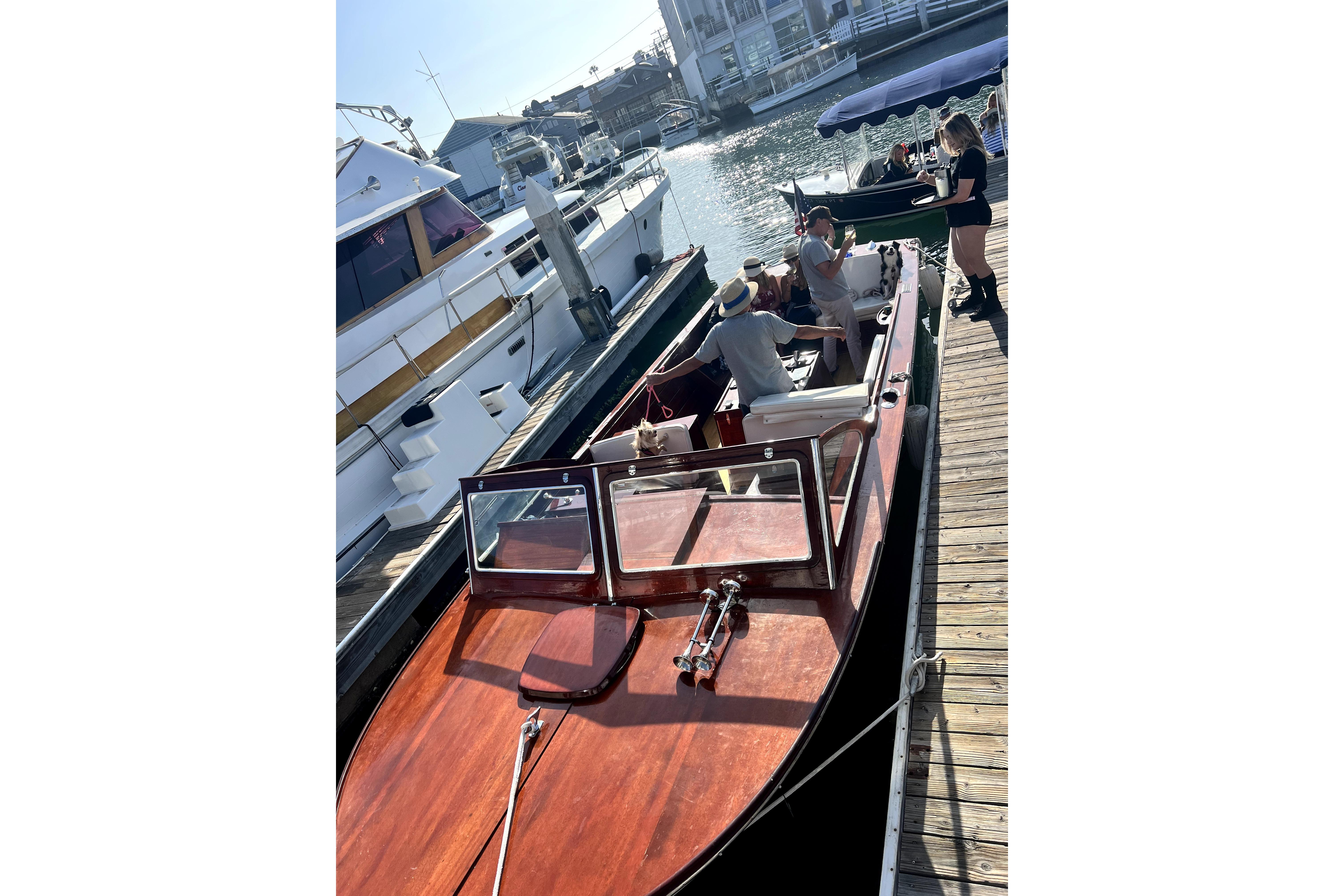 1964 Lyman 25 Sleeper boat docked, with people onboard, sunny day, marina background.
