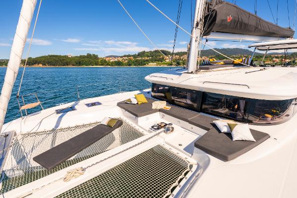 2025 Lagoon 43 catamaran with sunbathing area, cushions, and scenic coastal view.