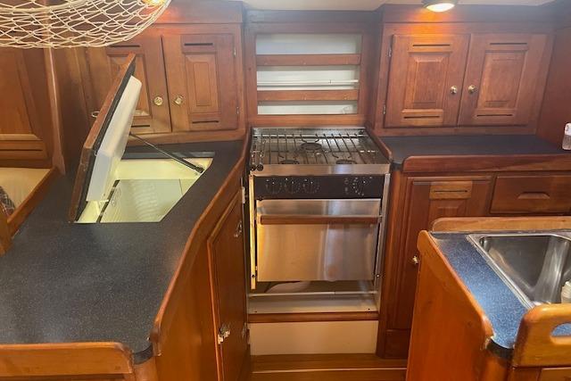 2001 Tartan 3700 yacht kitchen with wooden cabinets, stove, and sink.