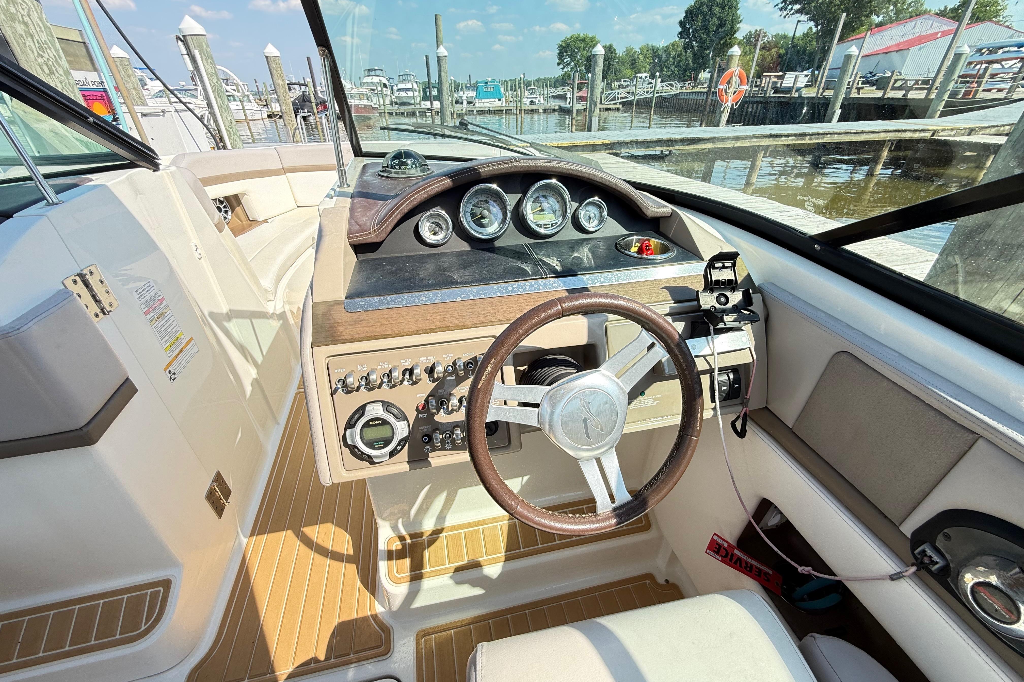 Interior view of 2011 Sea Ray 270 SLX boat cockpit with steering wheel and controls.
