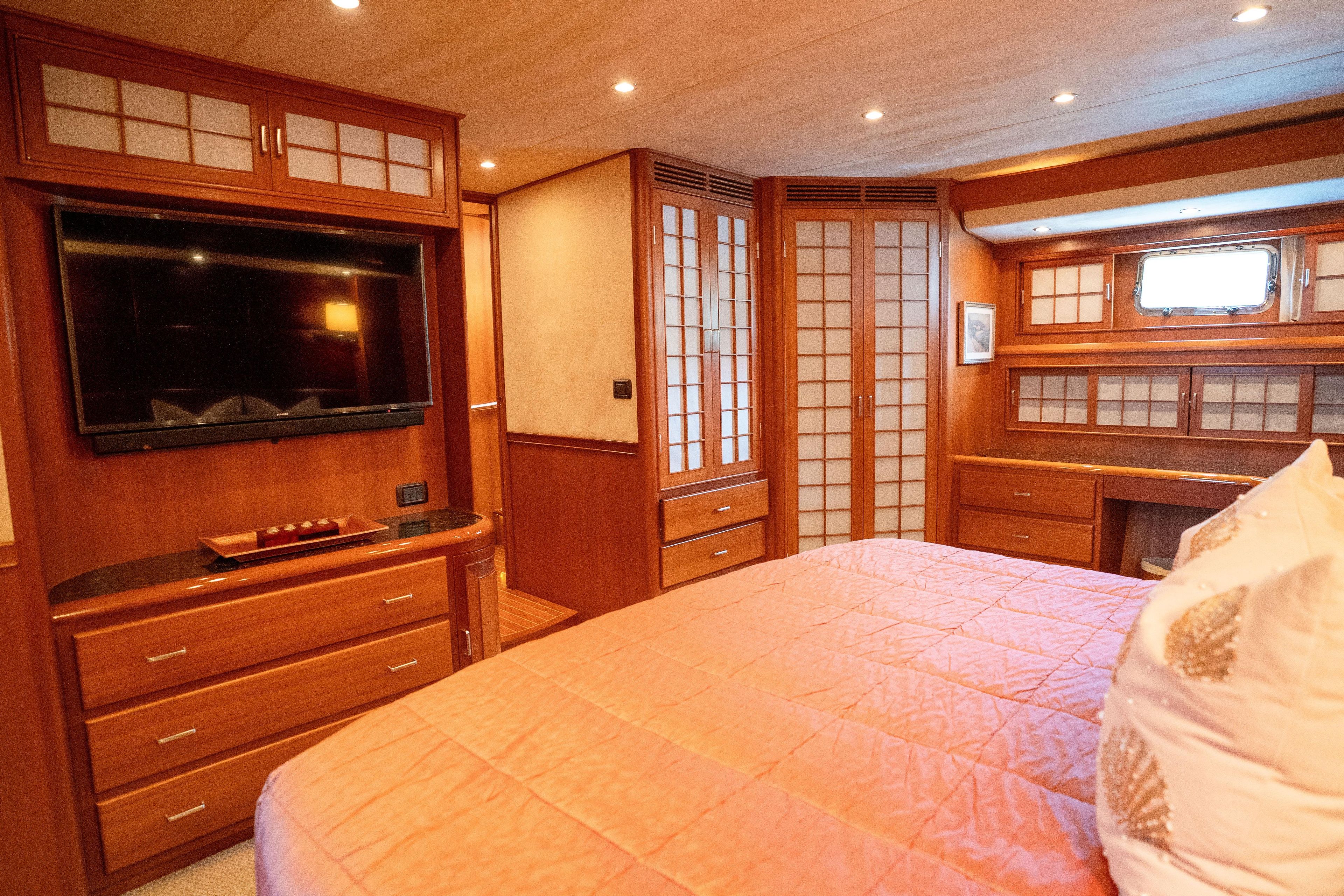 Luxurious 2006 Fleming 75 yacht bedroom with elegant wood paneling and modern amenities.