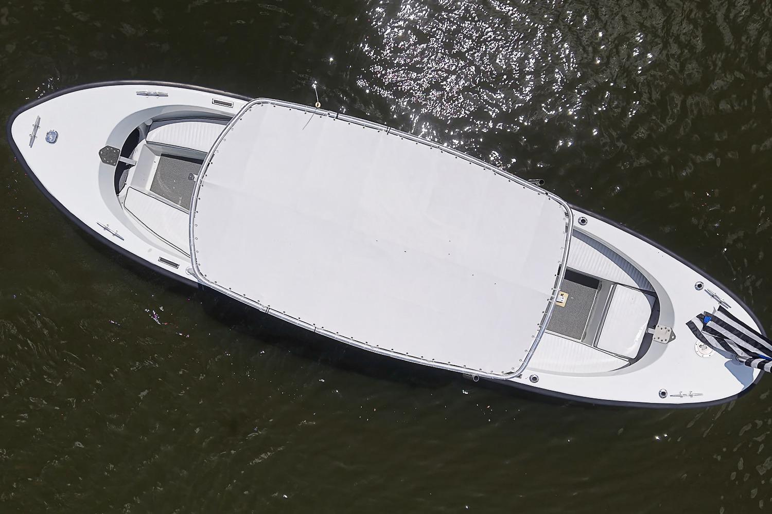 Aerial view of a custom 1969 boat with a large white canopy on water.