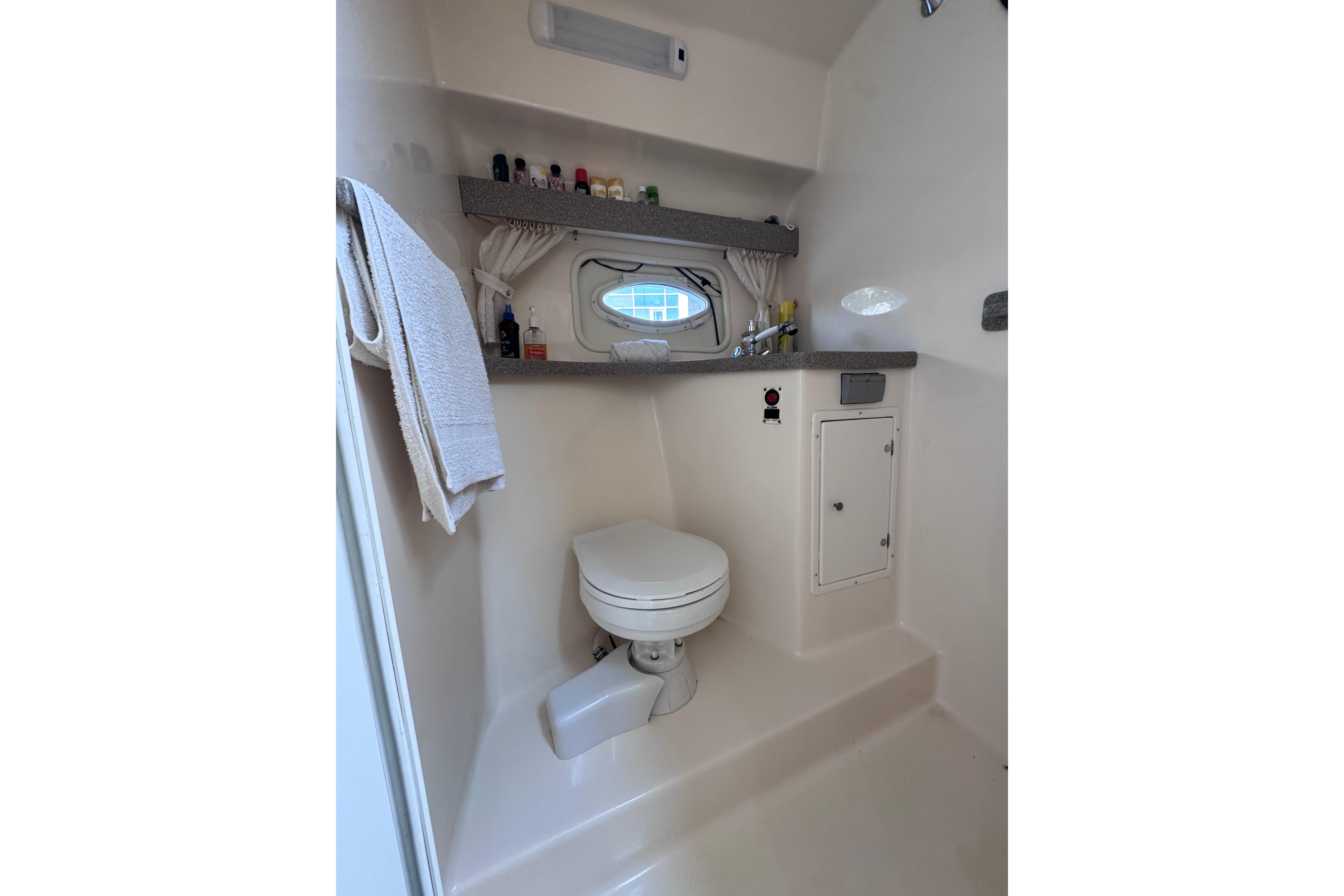 Bathroom interior of 2003 Rinker Fiesta Vee 312 boat, featuring toilet and storage.